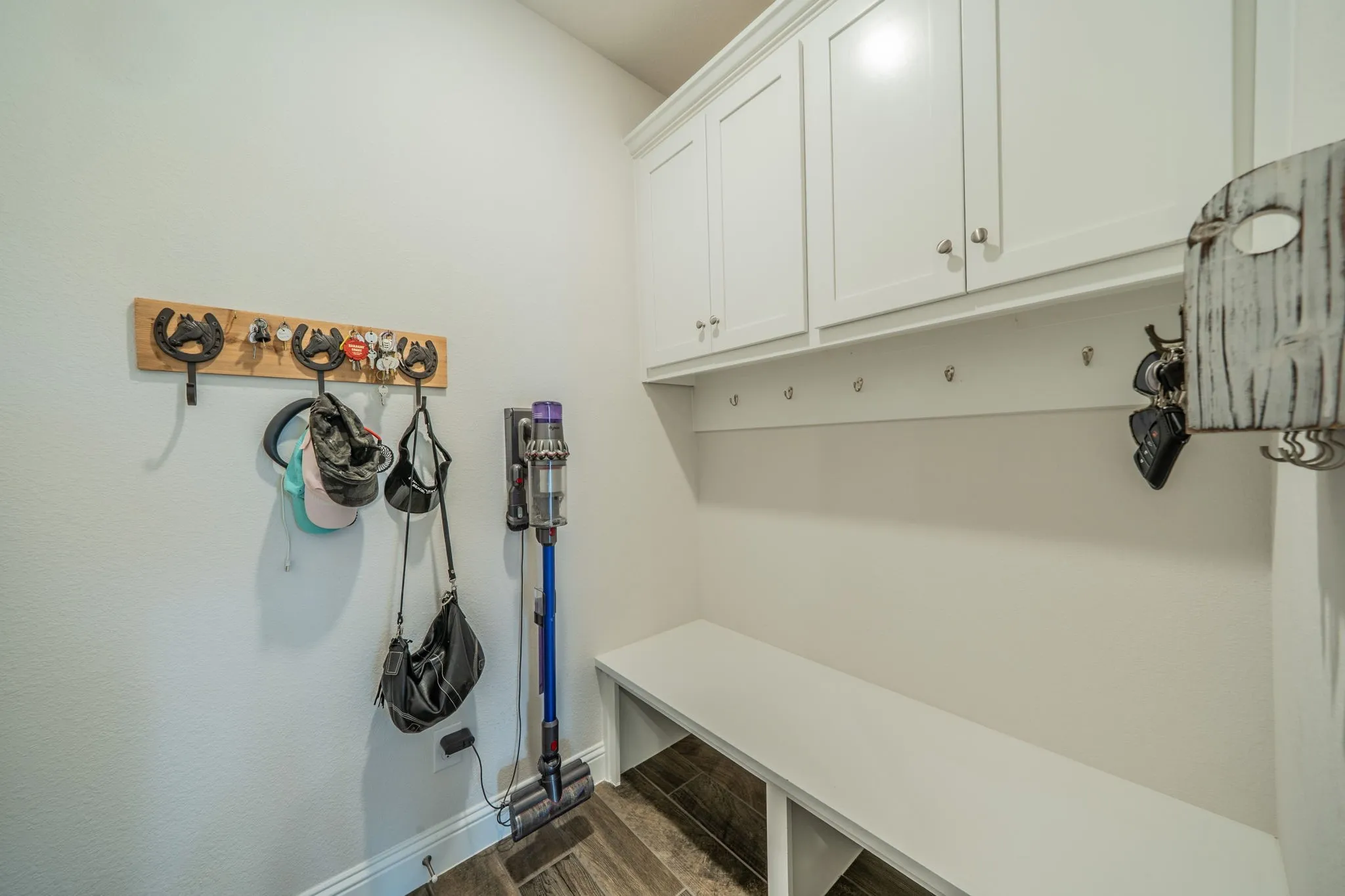 Garage entryway mudroom featuring built-in white cabinetry, a dedicated bench, and integrated coat hooks