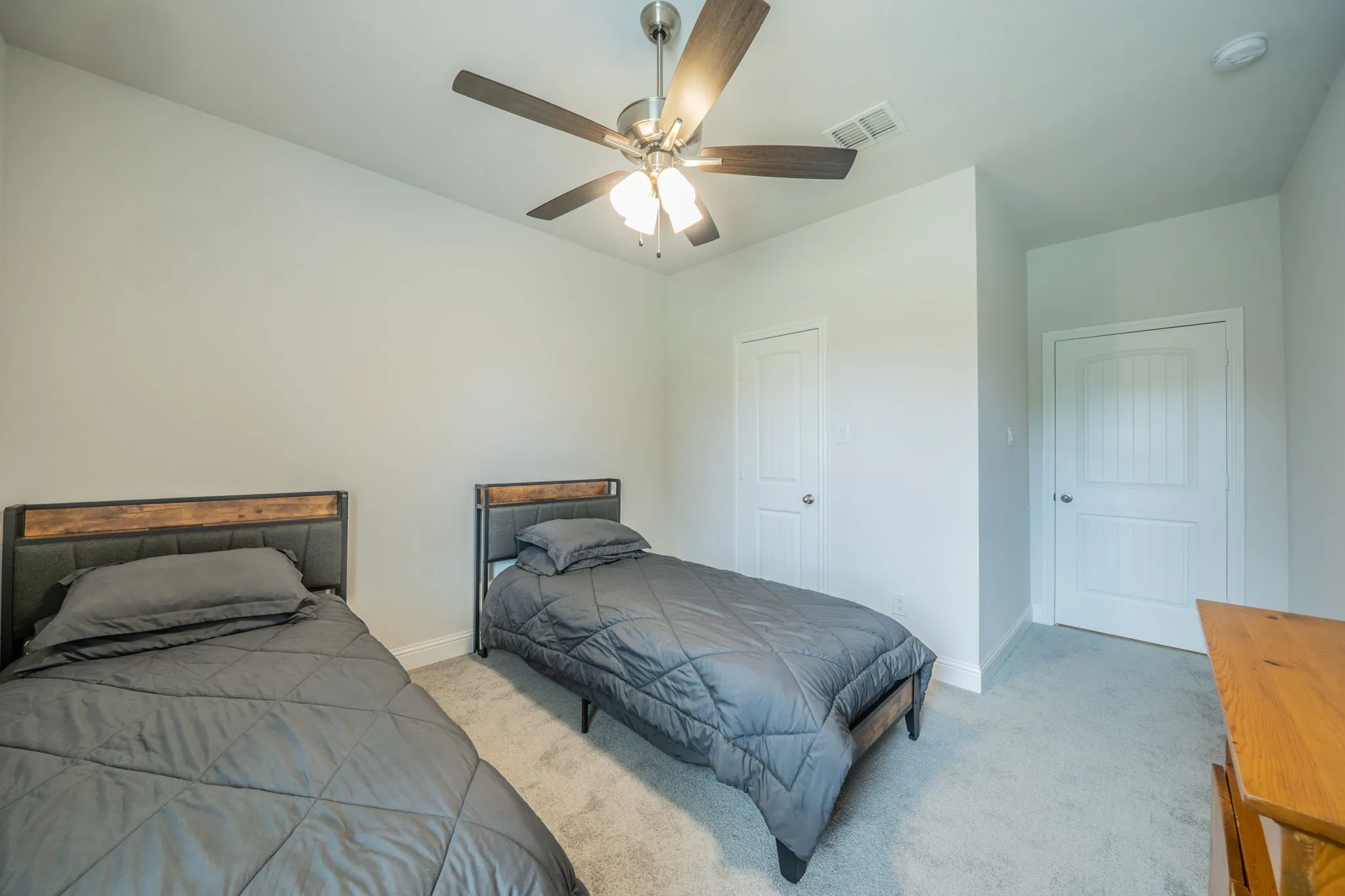 Carpeted room featuring a ceiling fan with integrated lighting, two white panel doors, and neutral wall tones