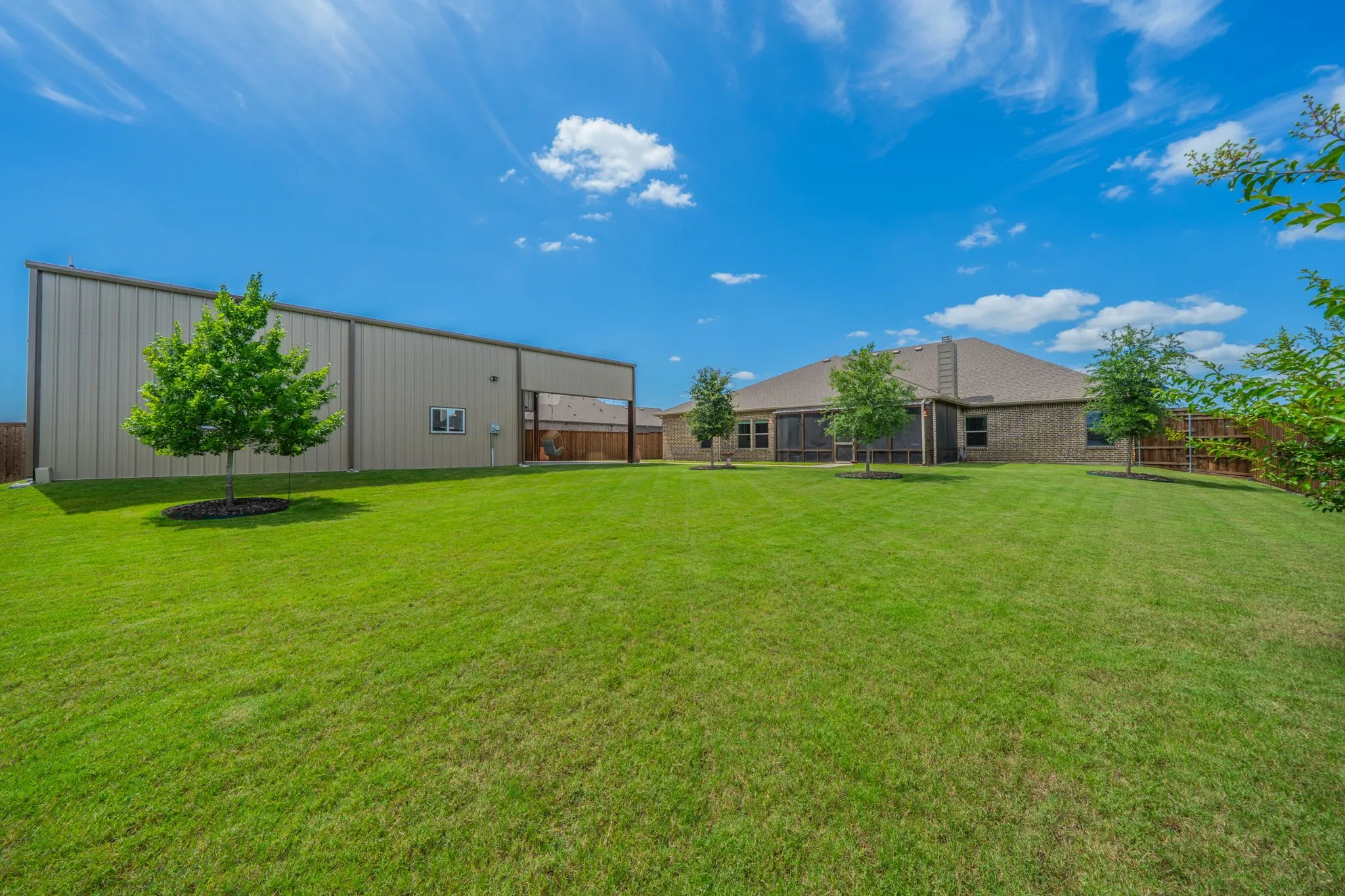 Expansive green lawn featuring a 1,200' workshop, a brick main residence, and mature trees