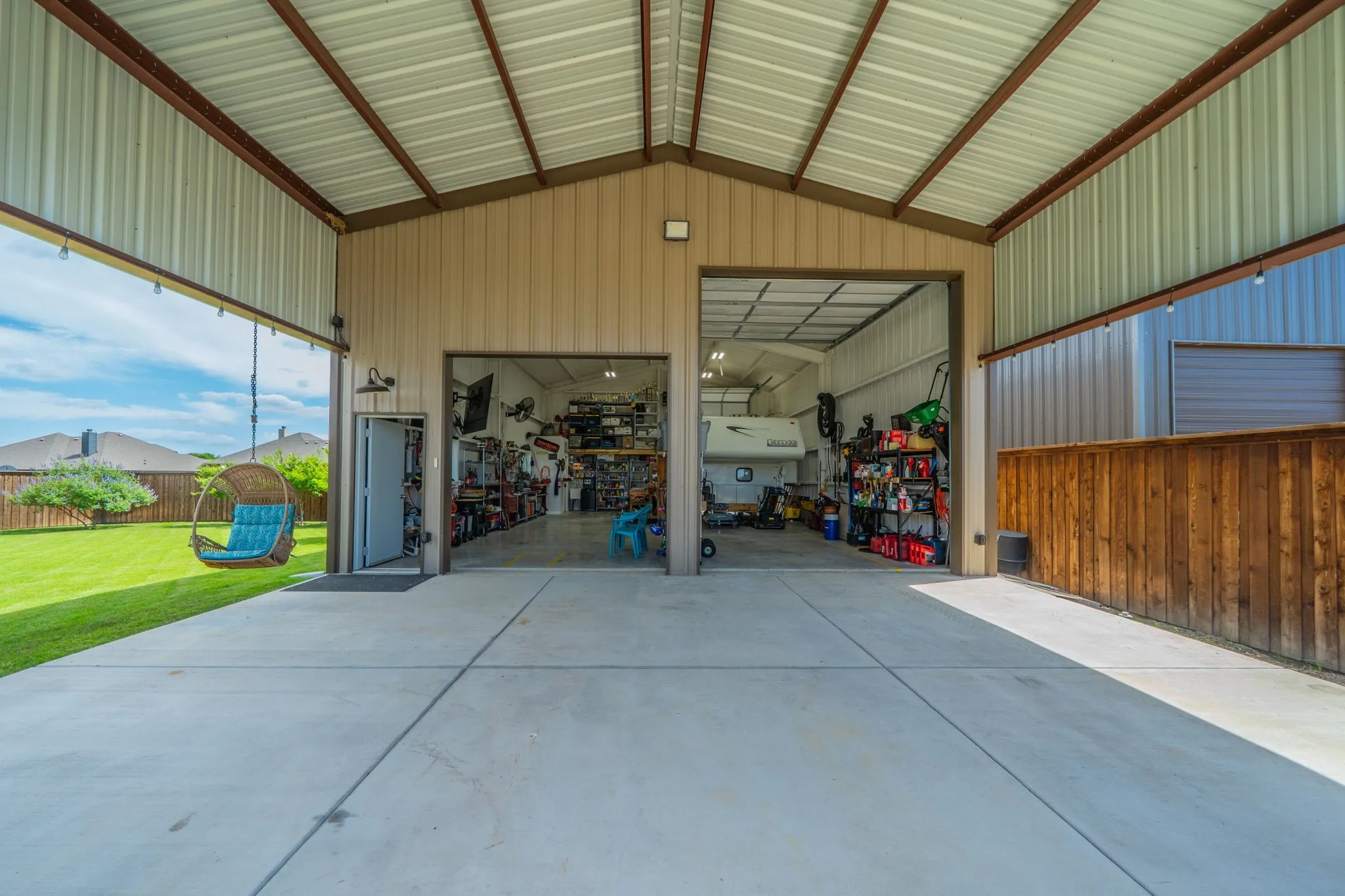 Expansive 30'x20' covered extension extending to a 30'x40' metal shop building with roll-up doors, a separate entry door, and a fully fenced yard