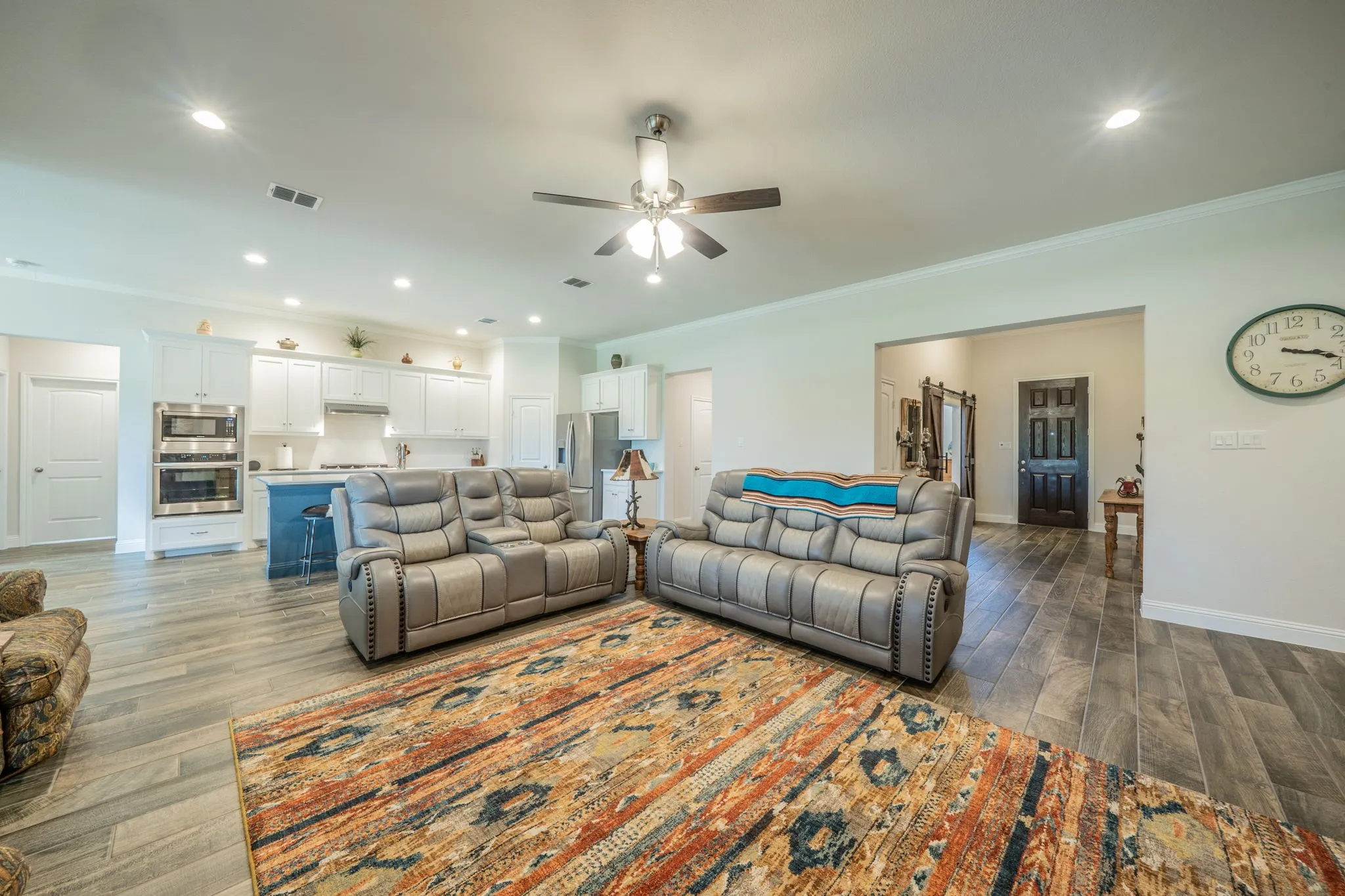 Open-concept living area featuring wood-finish tile flooring, recessed lighting, and a ceiling fan