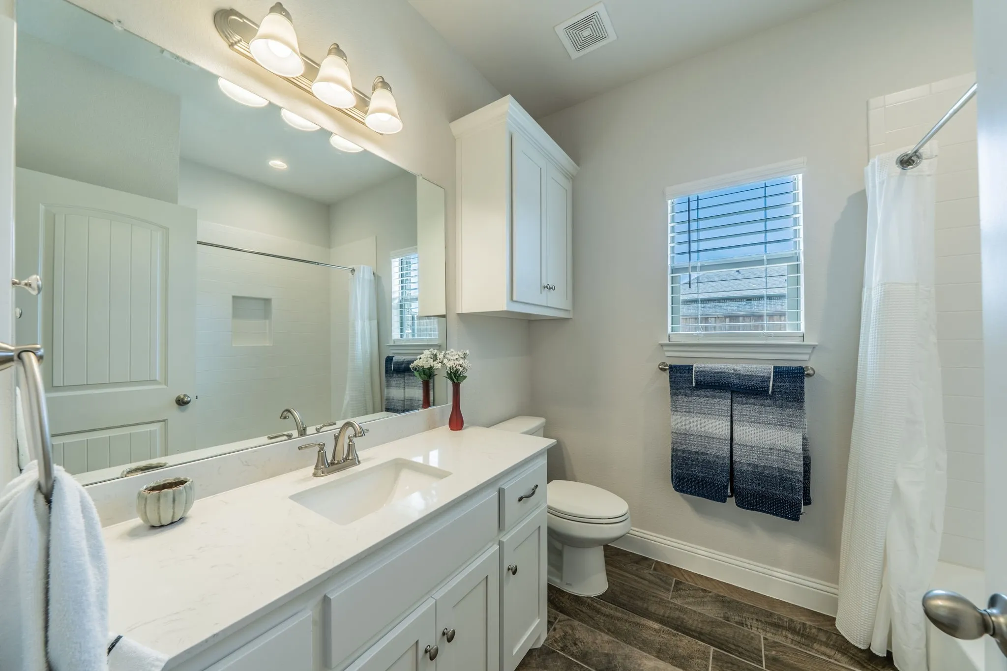 Full bathroom featuring a single vanity with a white countertop and undermount sink, brushed nickel faucet, and a large wall-mounted mirror