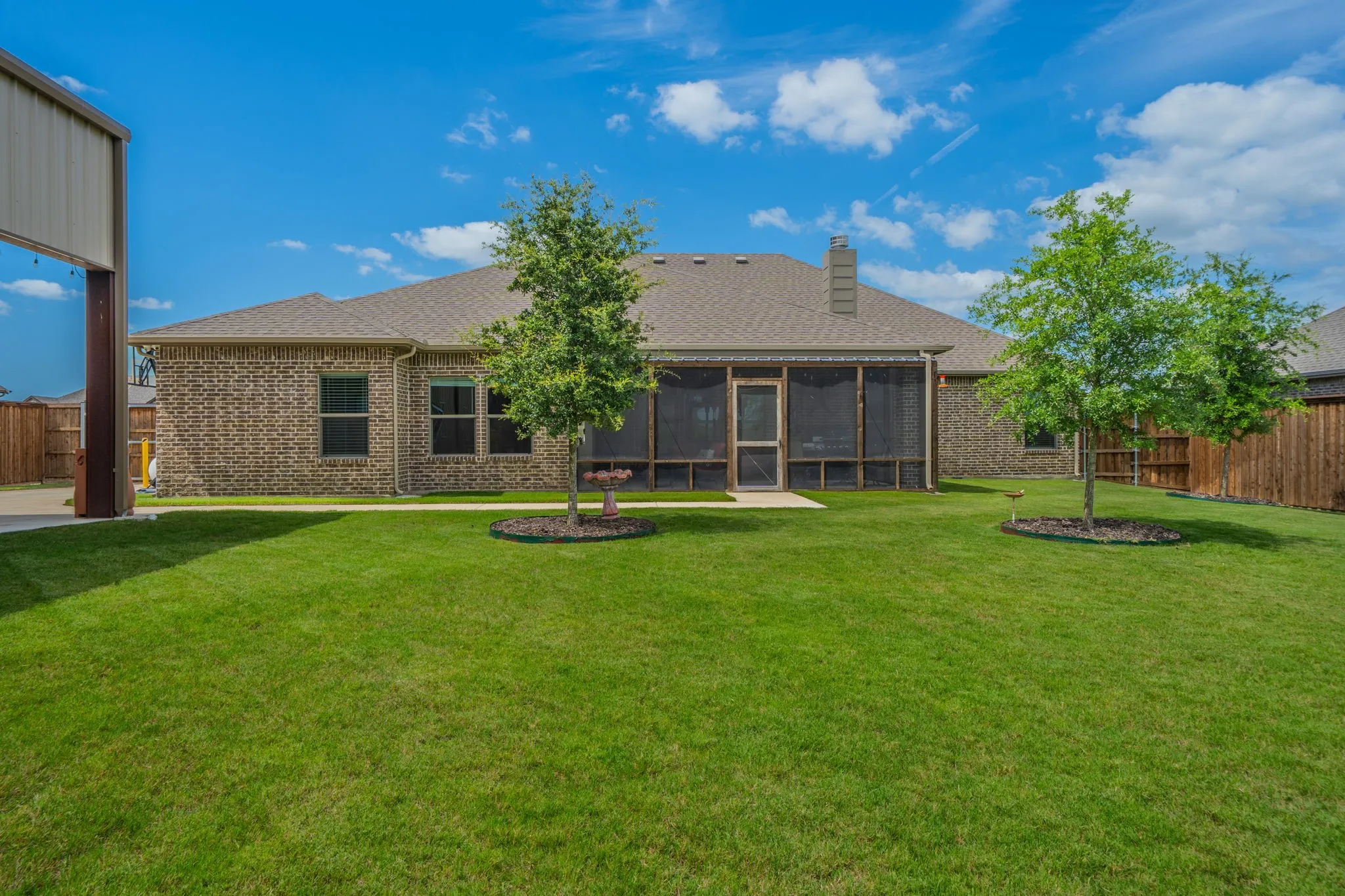 Expansive green lawn with a full brick exterior and a screened porch