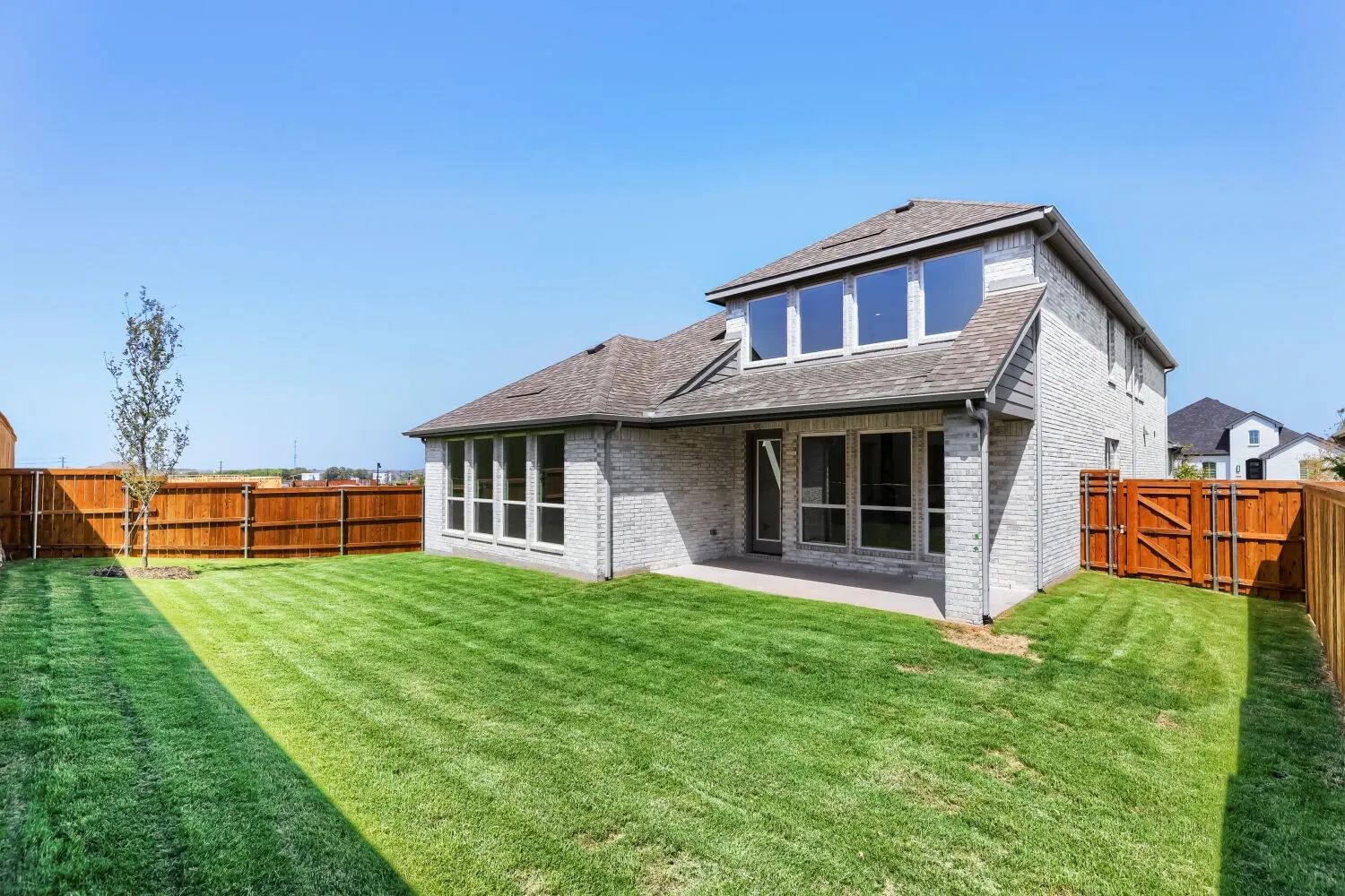 Expansive backyard featuring a manicured lawn, full wood fencing, and a concrete patio