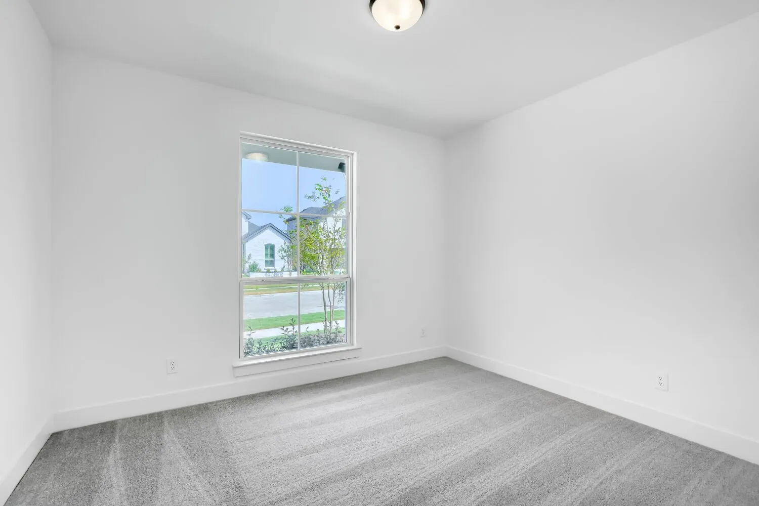 Recessed window with white trim, neutral wall color, grey patterned carpet, and a flush mount ceiling light