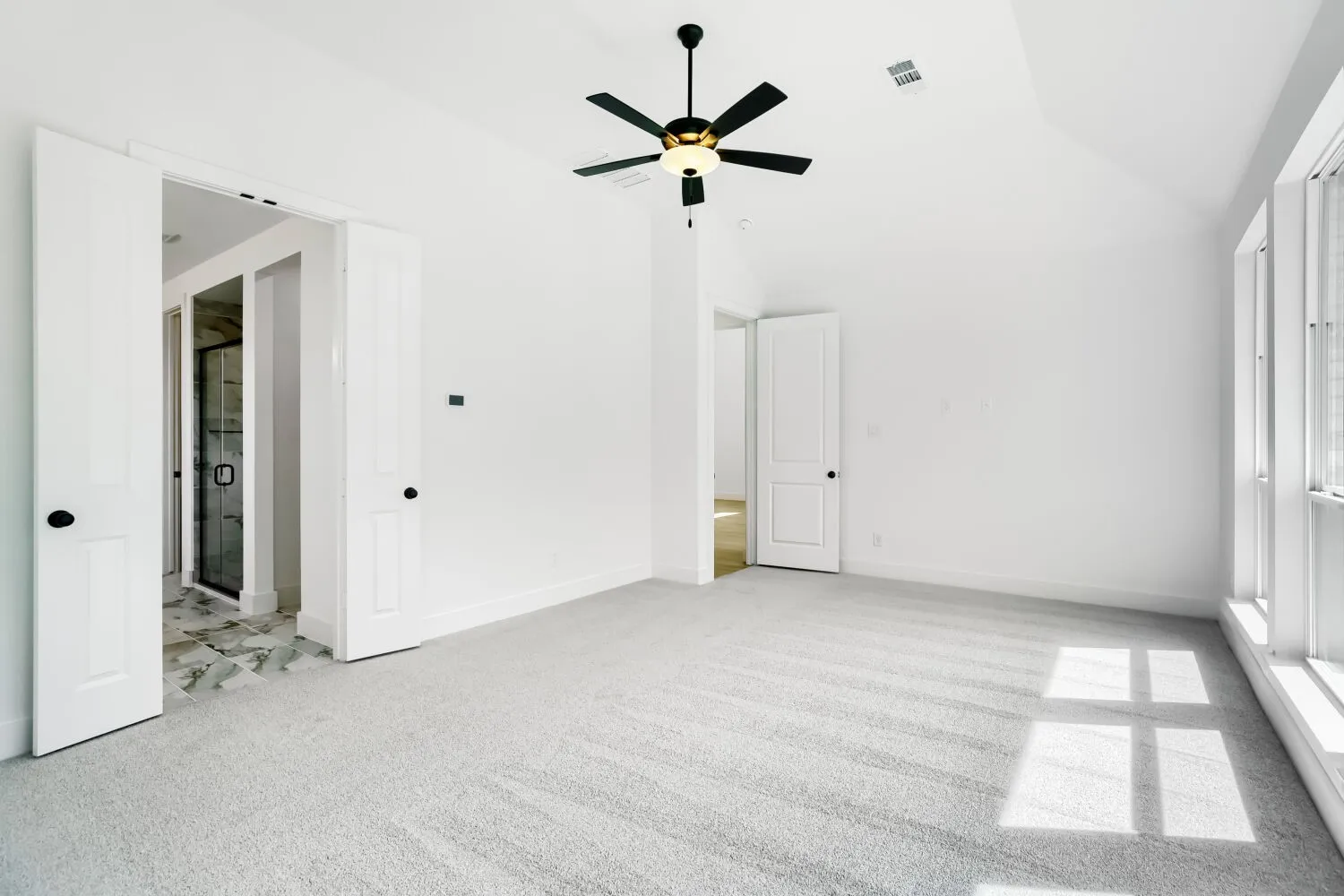 Vaulted ceiling featuring a ceiling fan, light gray carpet, and multiple windows
