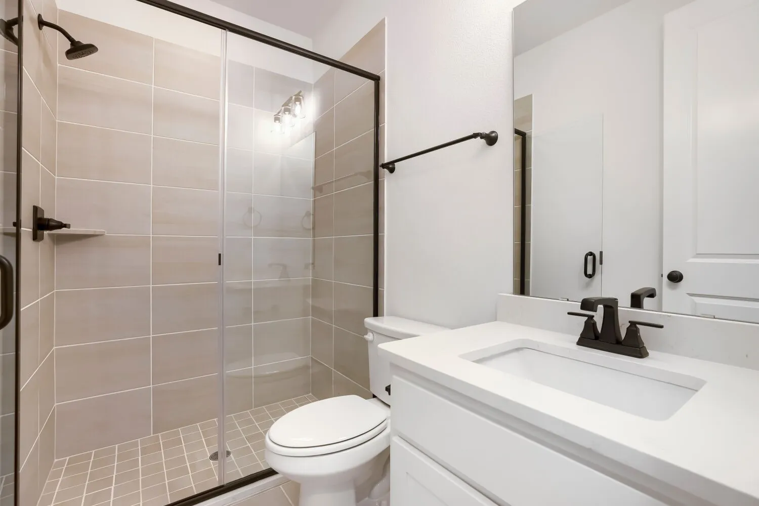 Walk-in shower with clear glass enclosure and light-toned tile surround