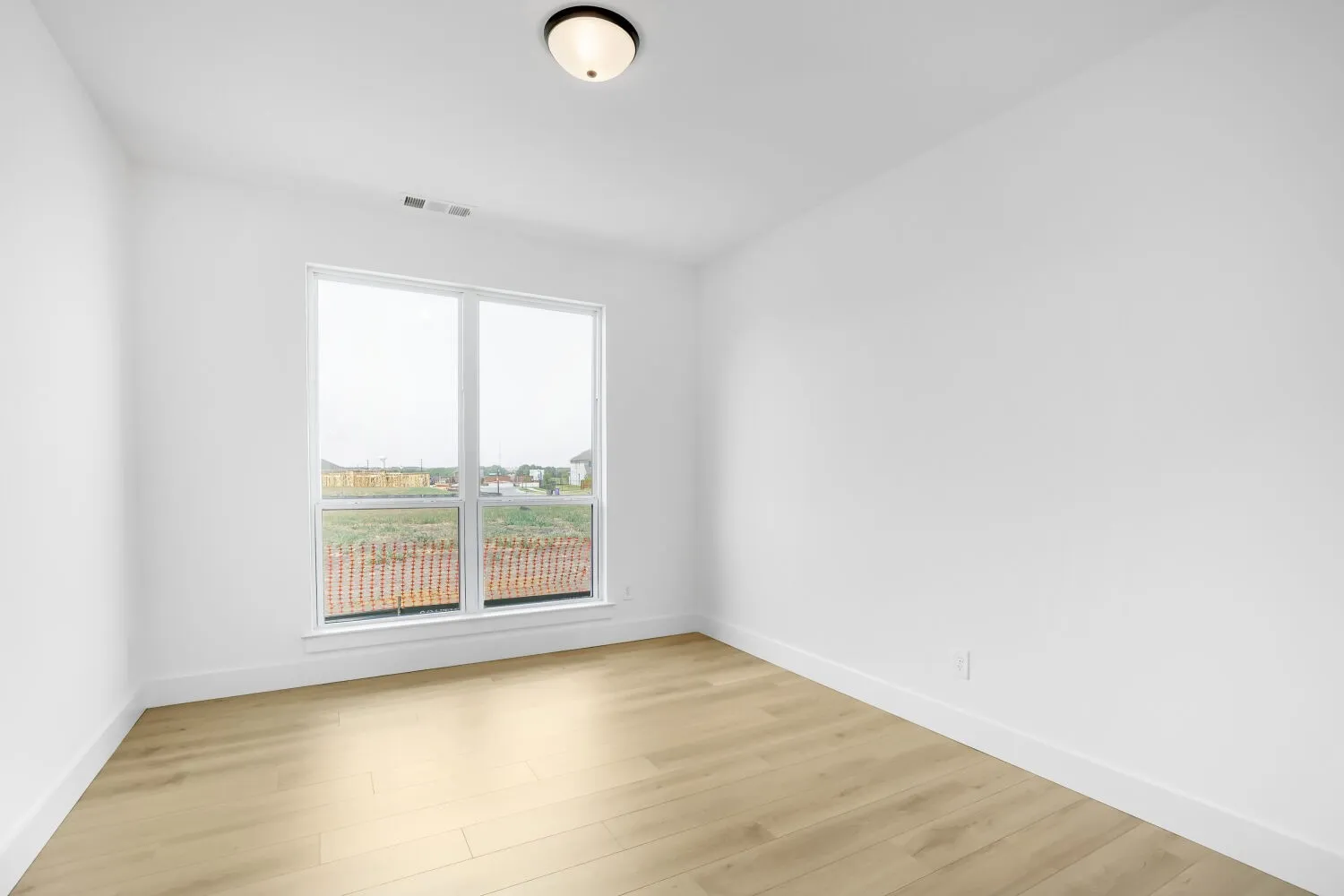 Bright interior space featuring light wood-finish flooring, white walls, and a large window