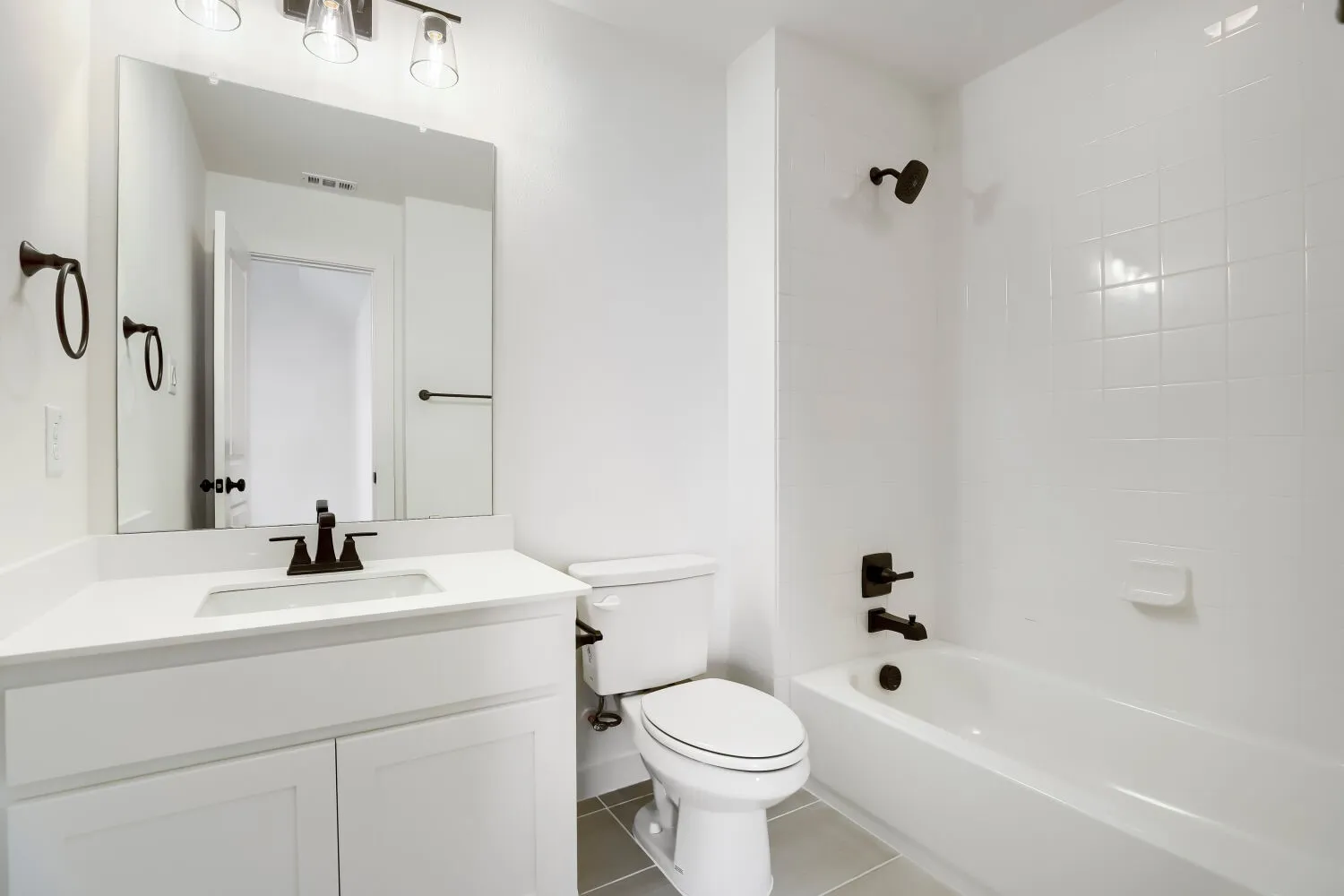 White vanity with a solid surface countertop, an undermount sink, and matte black fixtures