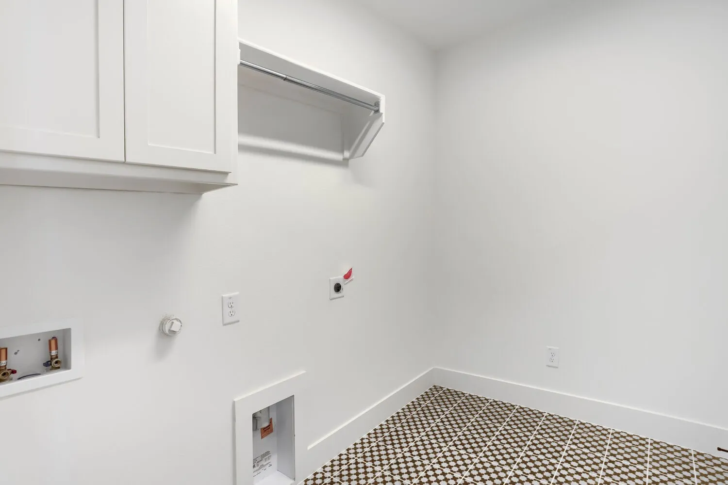 White shaker cabinetry, wall-mounted clothes rod, white walls, and patterned tile flooring