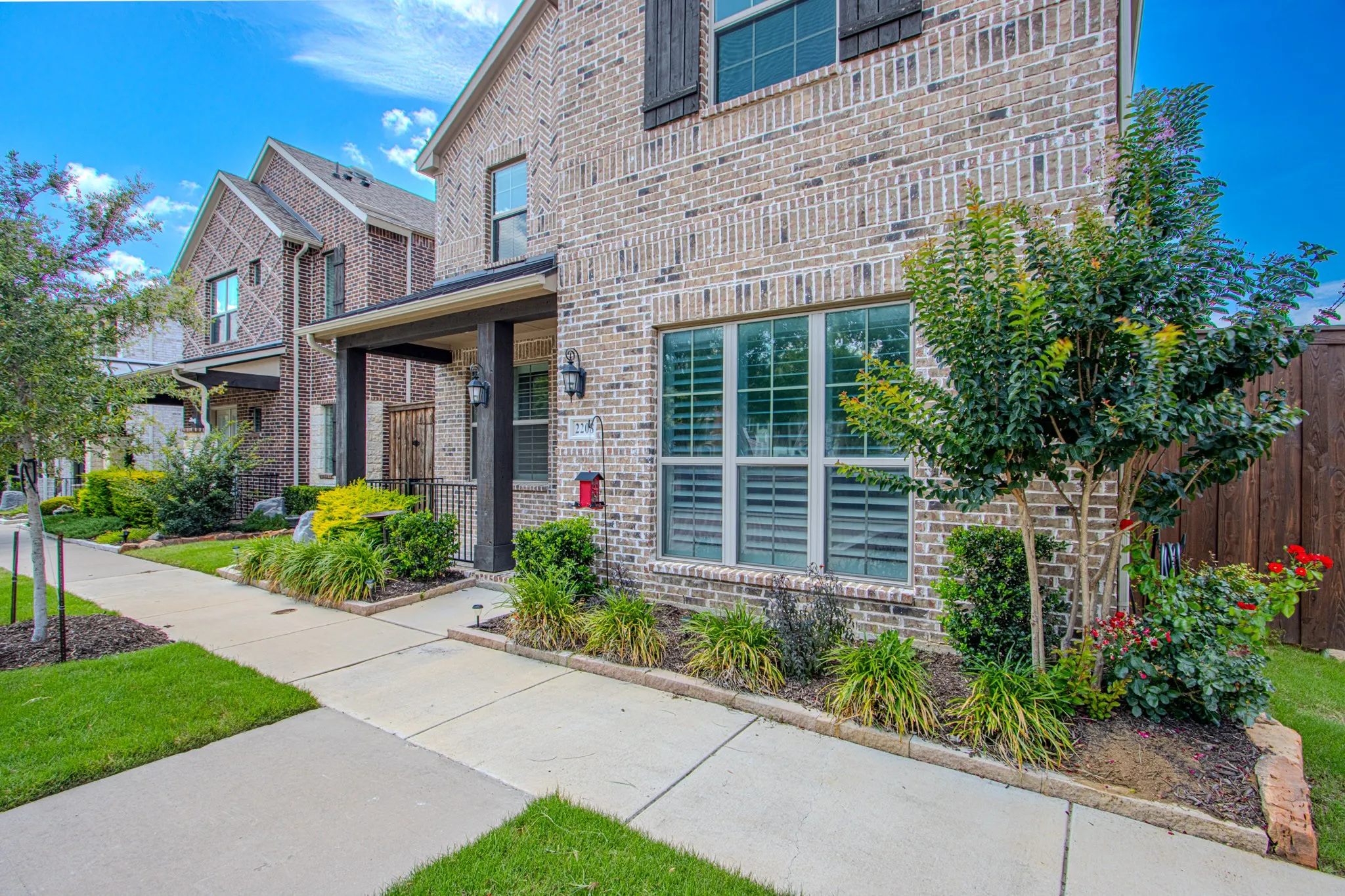 Brick exterior featuring a covered entry porch, dark wood shutters, and prominent windows with internal blinds