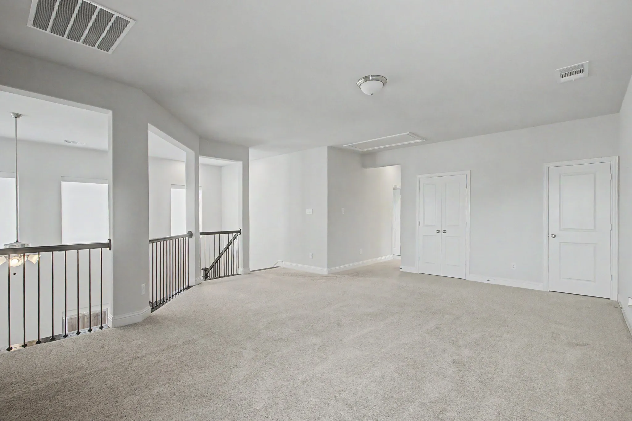 Spacious carpeted bonus room featuring white walls and ceiling, recessed air vent, semi-flush mount ceiling light, and white paneled doors
