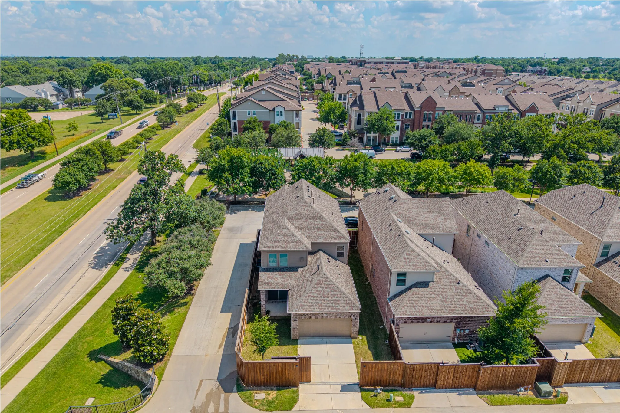 Aerial perspective showcasing residential properties with a primary two-story dwelling featuring a light-colored façade and an attached garage