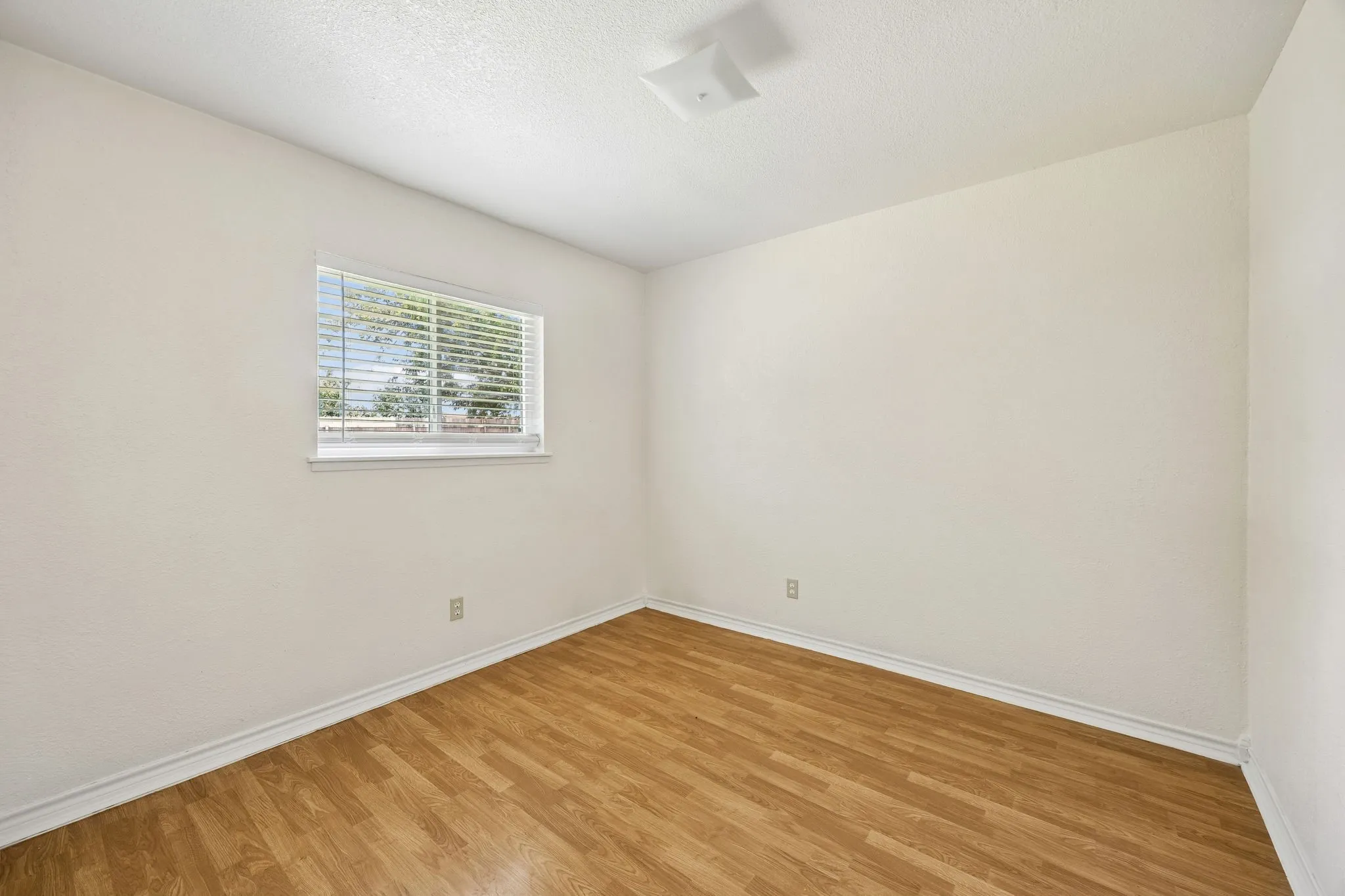 Room featuring wood-finish flooring, white baseboards, and neutral wall paint