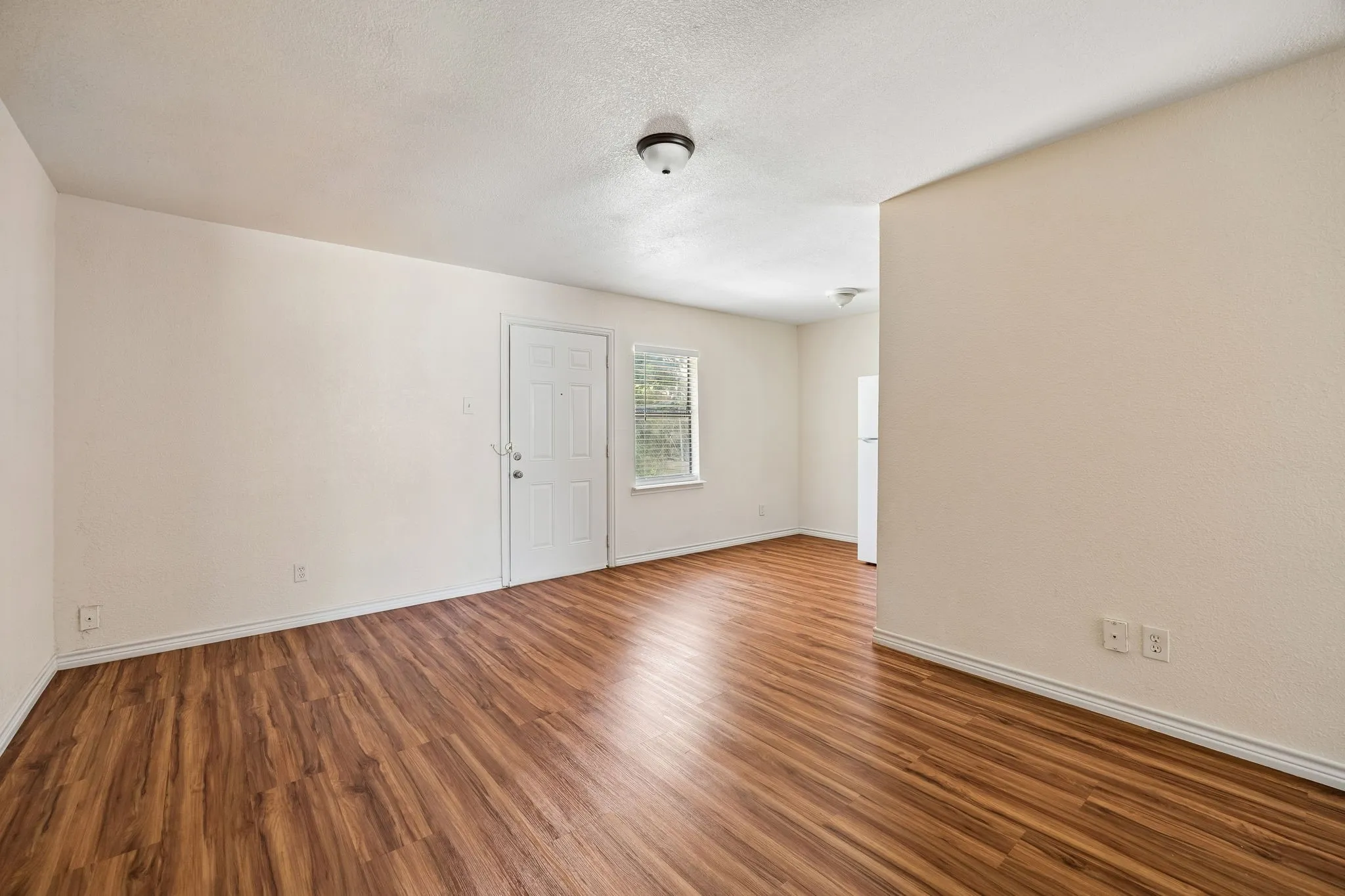 Open concept living space featuring wood-finish flooring, neutral wall tones, and a bright window