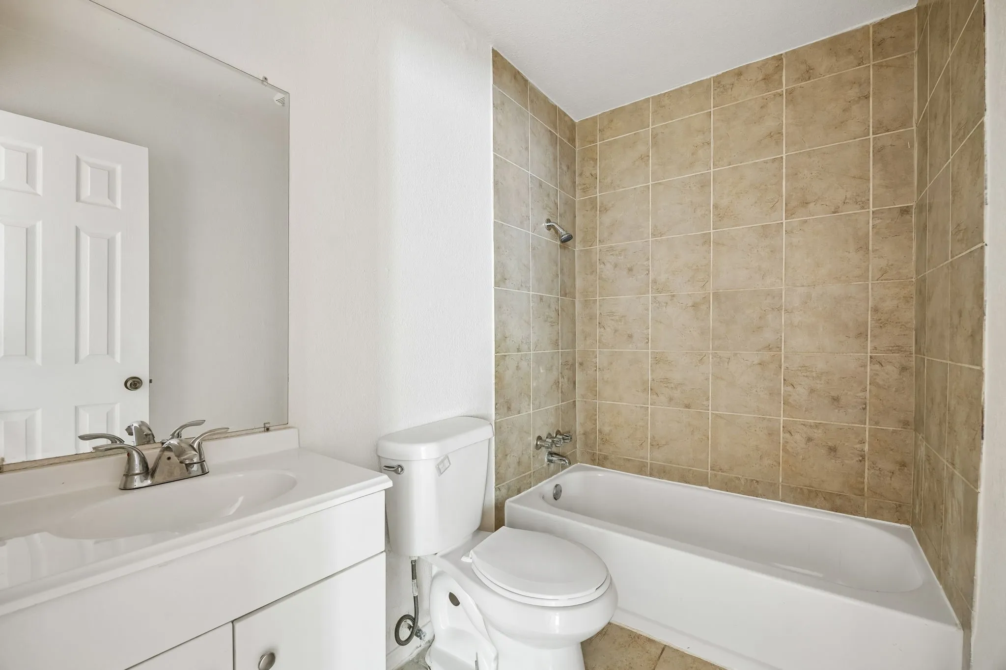 Bathroom featuring a white vanity with an integrated sink, a chrome faucet, and a wall-mounted mirror