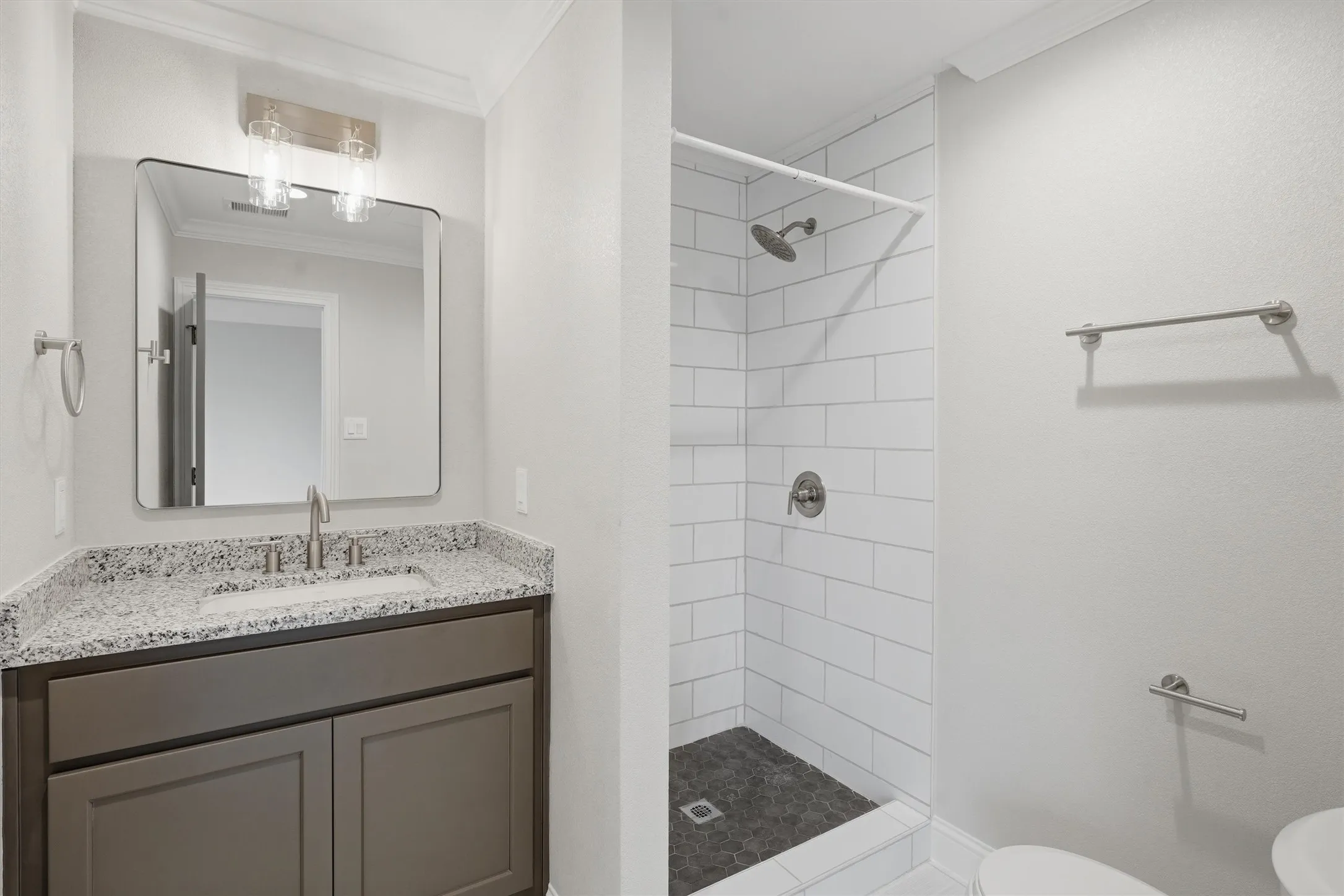 Bathroom vanity featuring a granite countertop with an undermount sink, brushed nickel faucet, and a contemporary mirror