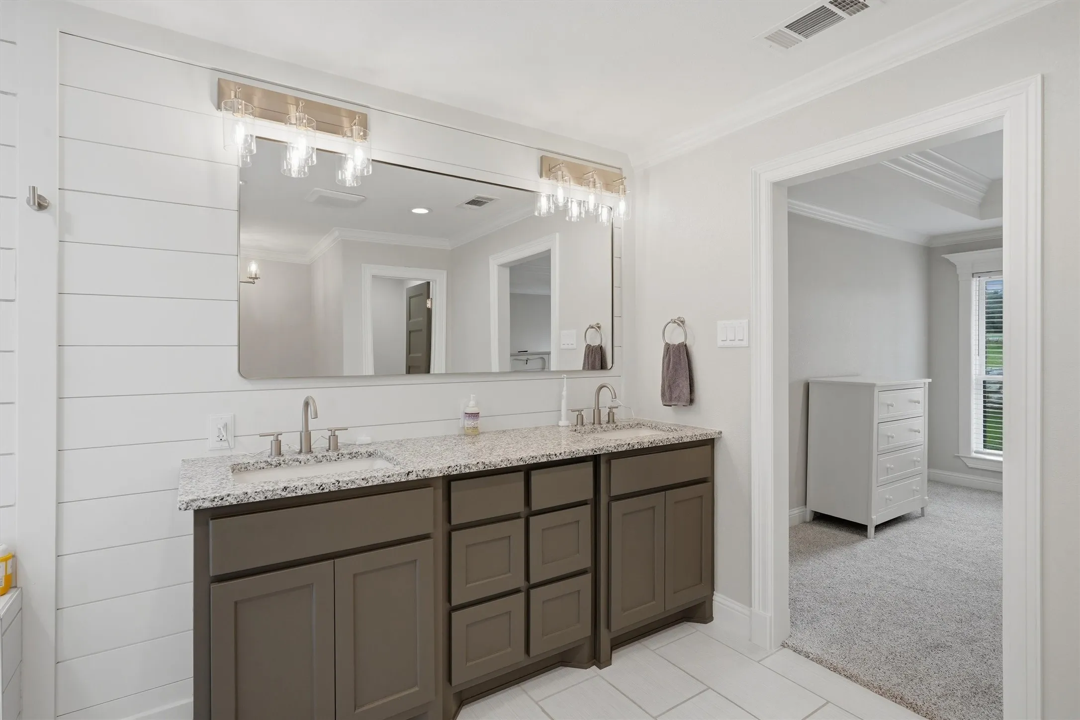 Bathroom vanity featuring dual sinks with granite countertops and brushed nickel faucets