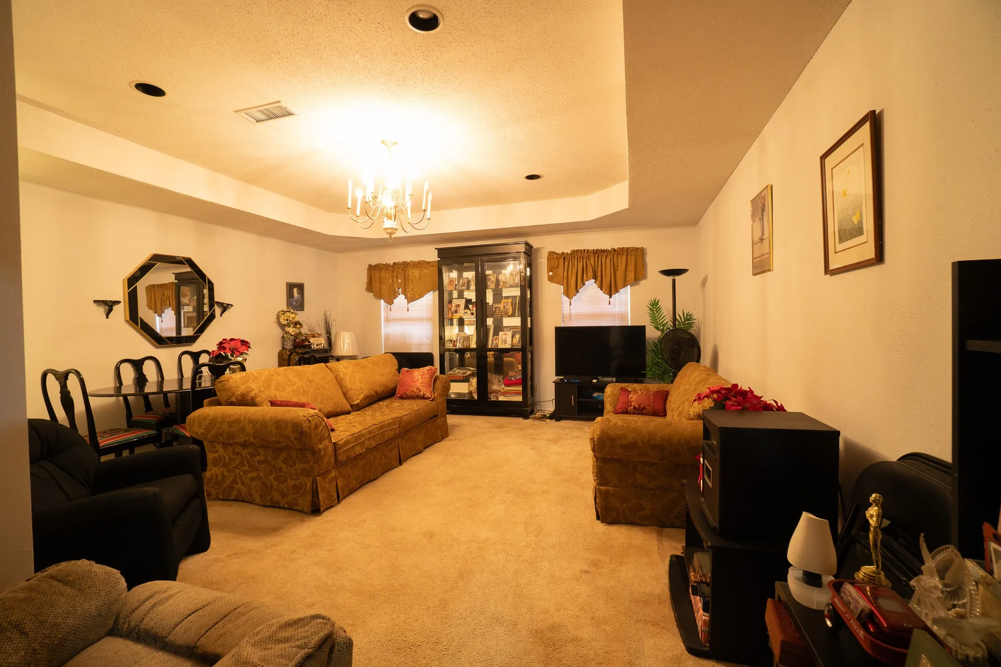 Spacious living area featuring a tray ceiling with recessed lighting and a central chandelier