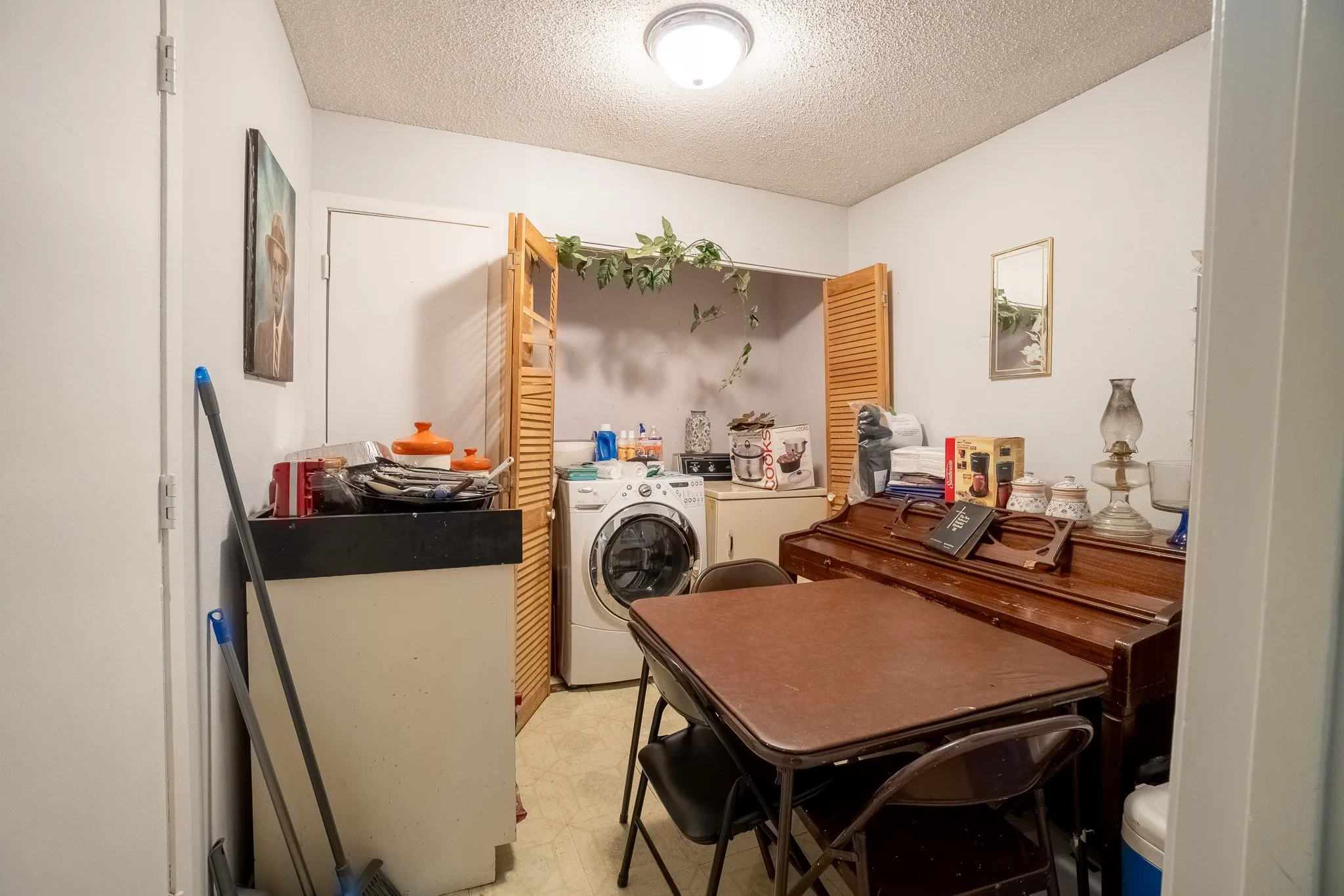Laundry area featuring a front-loading washing machine and wood-louvered bi-fold doors