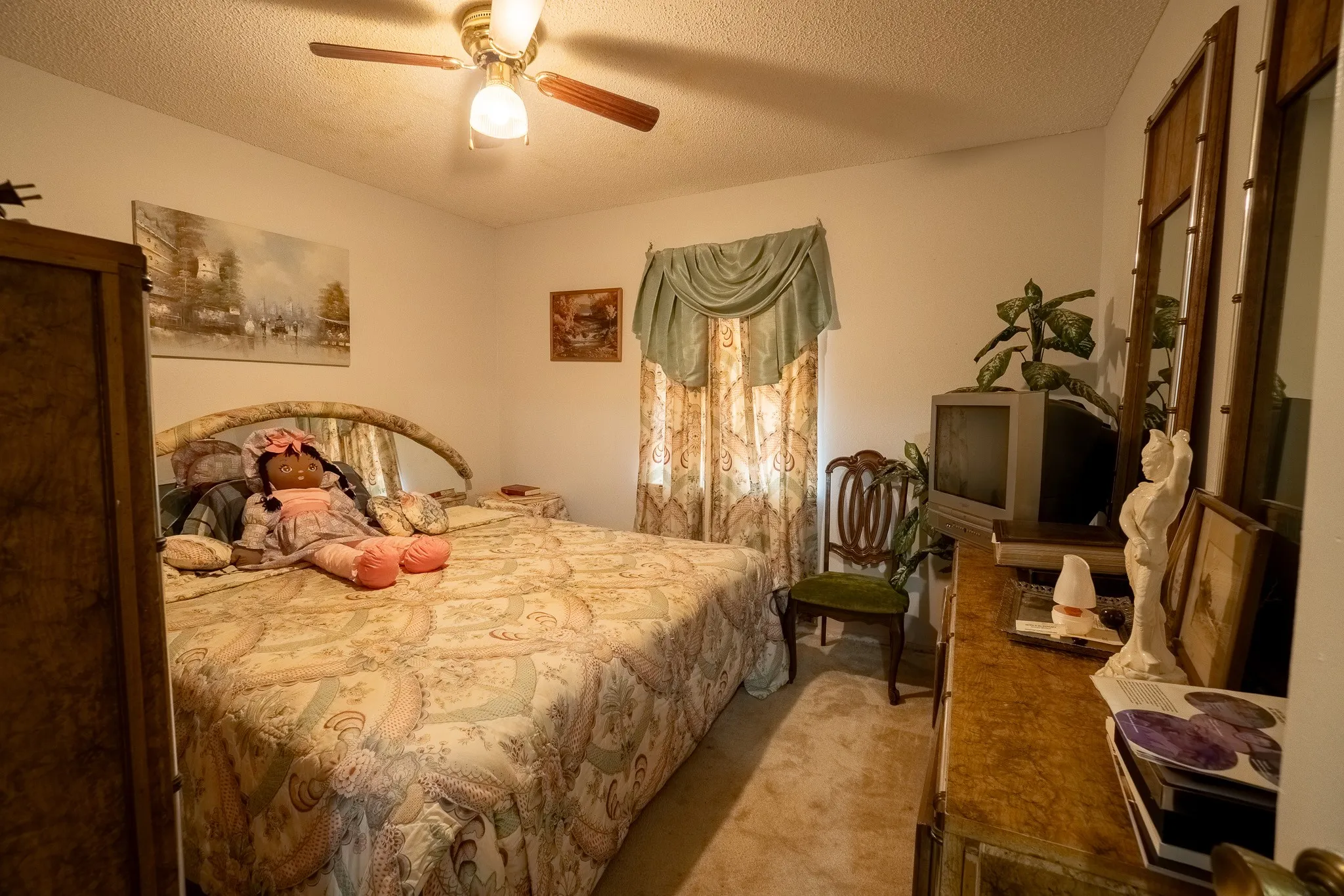 Bedroom featuring a ceiling fan with integrated lighting, a window with drapery, and neutral-toned carpeting