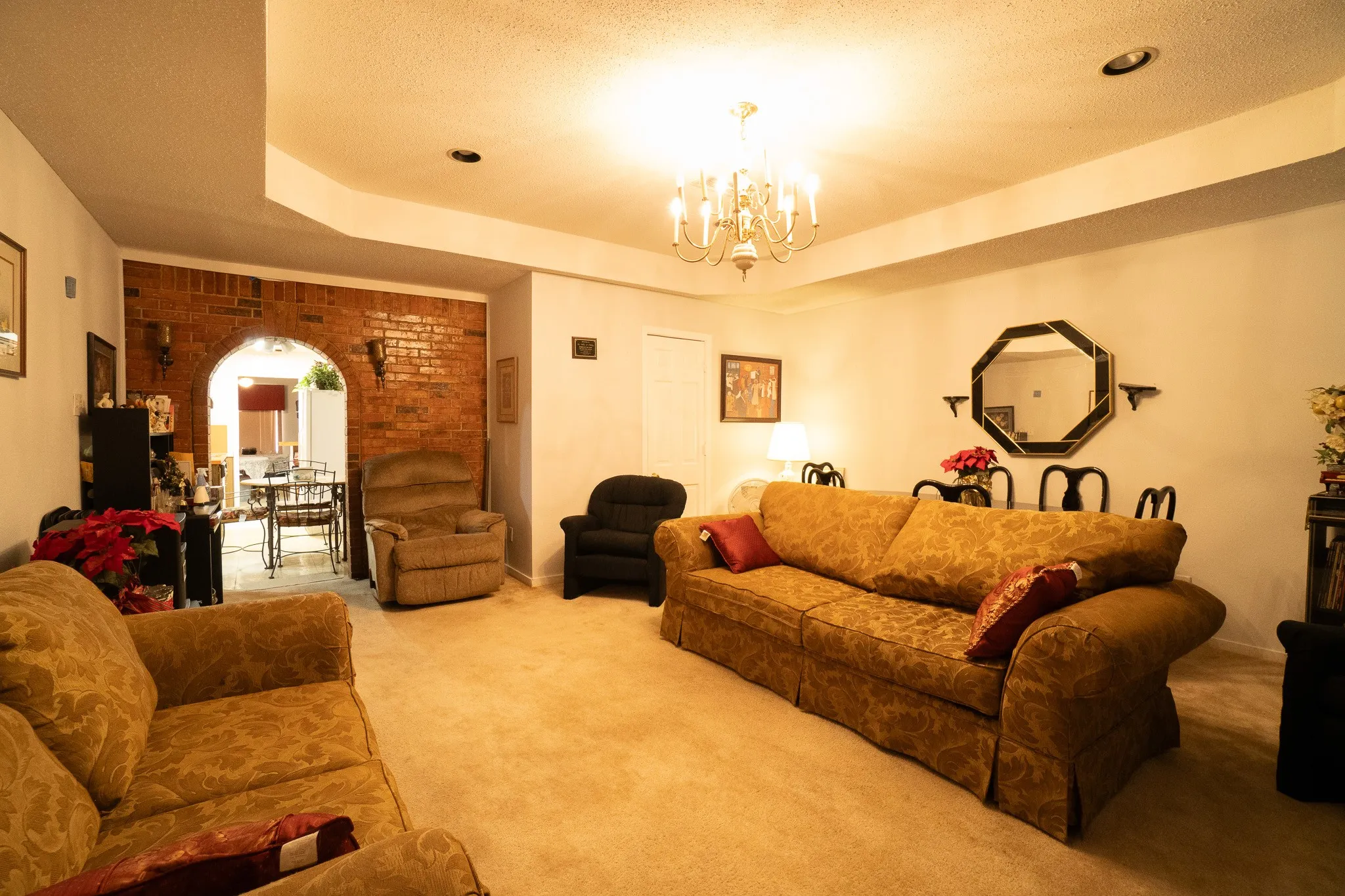 Spacious living area featuring neutral carpet flooring, recessed lighting, and a brass chandelier