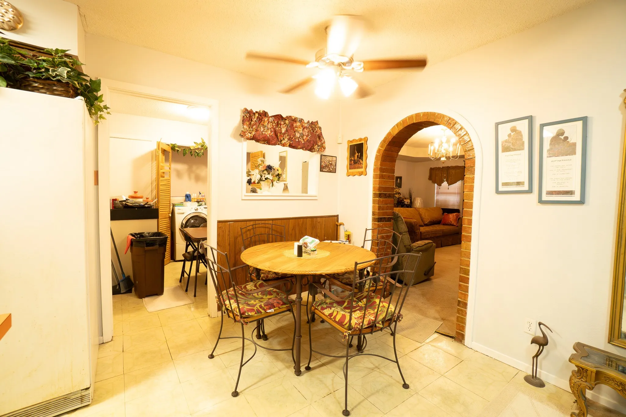 Dining area featuring tile flooring, a ceiling fan, and a brick-archway opening to an adjacent room