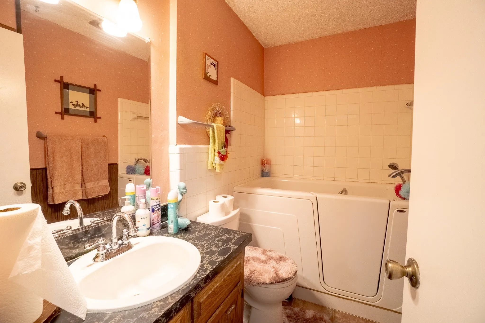 Bathroom featuring a walk-in bathtub, white tile surround, and a vanity with a dark countertop