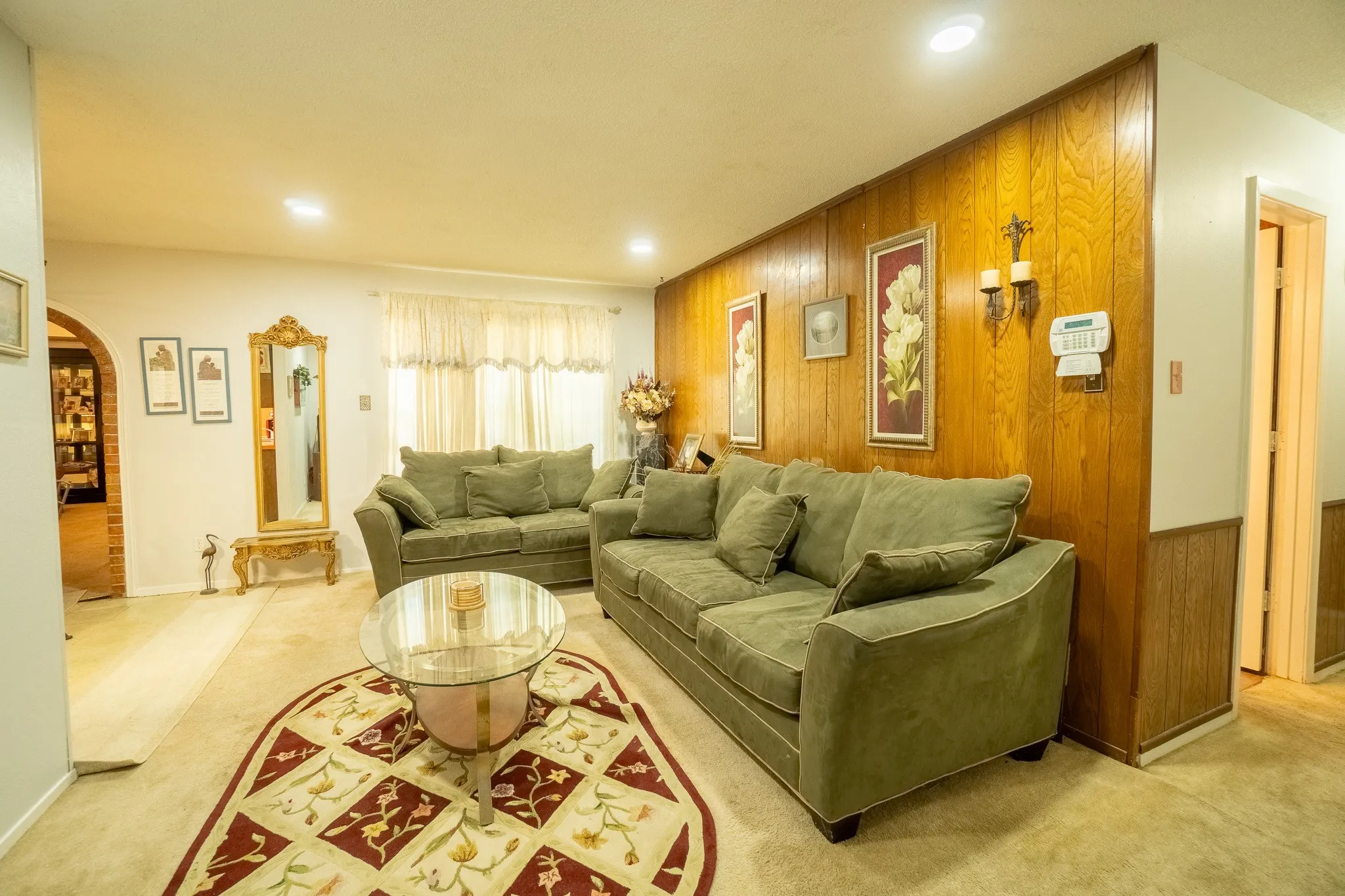 Living room featuring wood paneling, recessed lighting, and an arched entryway