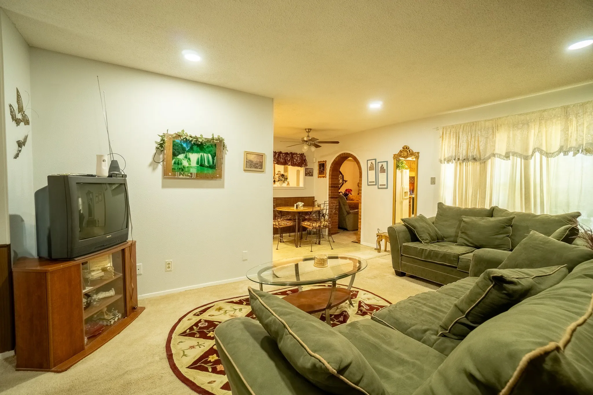 Spacious living area featuring light-colored carpeting, a decorative area rug, and recessed lighting