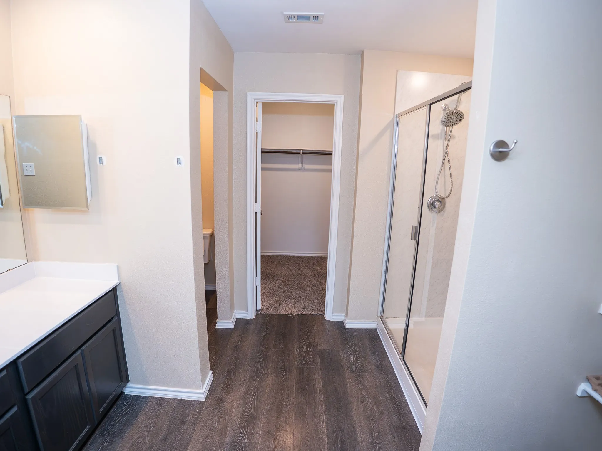 Contemporary bathroom featuring dark wood-finish cabinetry, a white countertop, and wood-finish flooring