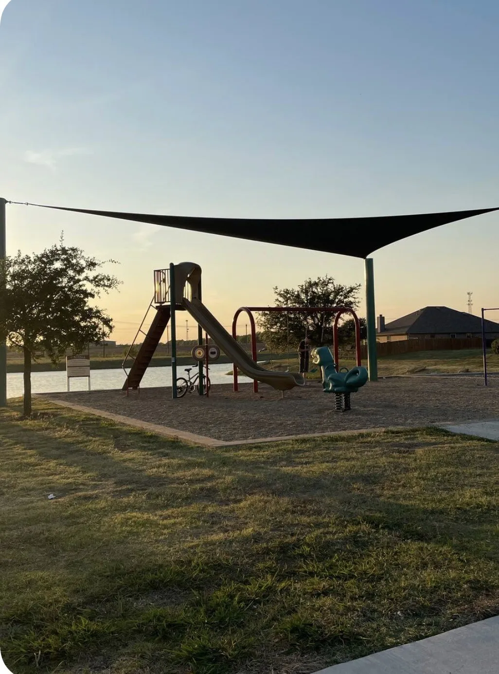 Community playground featuring a slide, swings, and spring rider over a bark chip surface