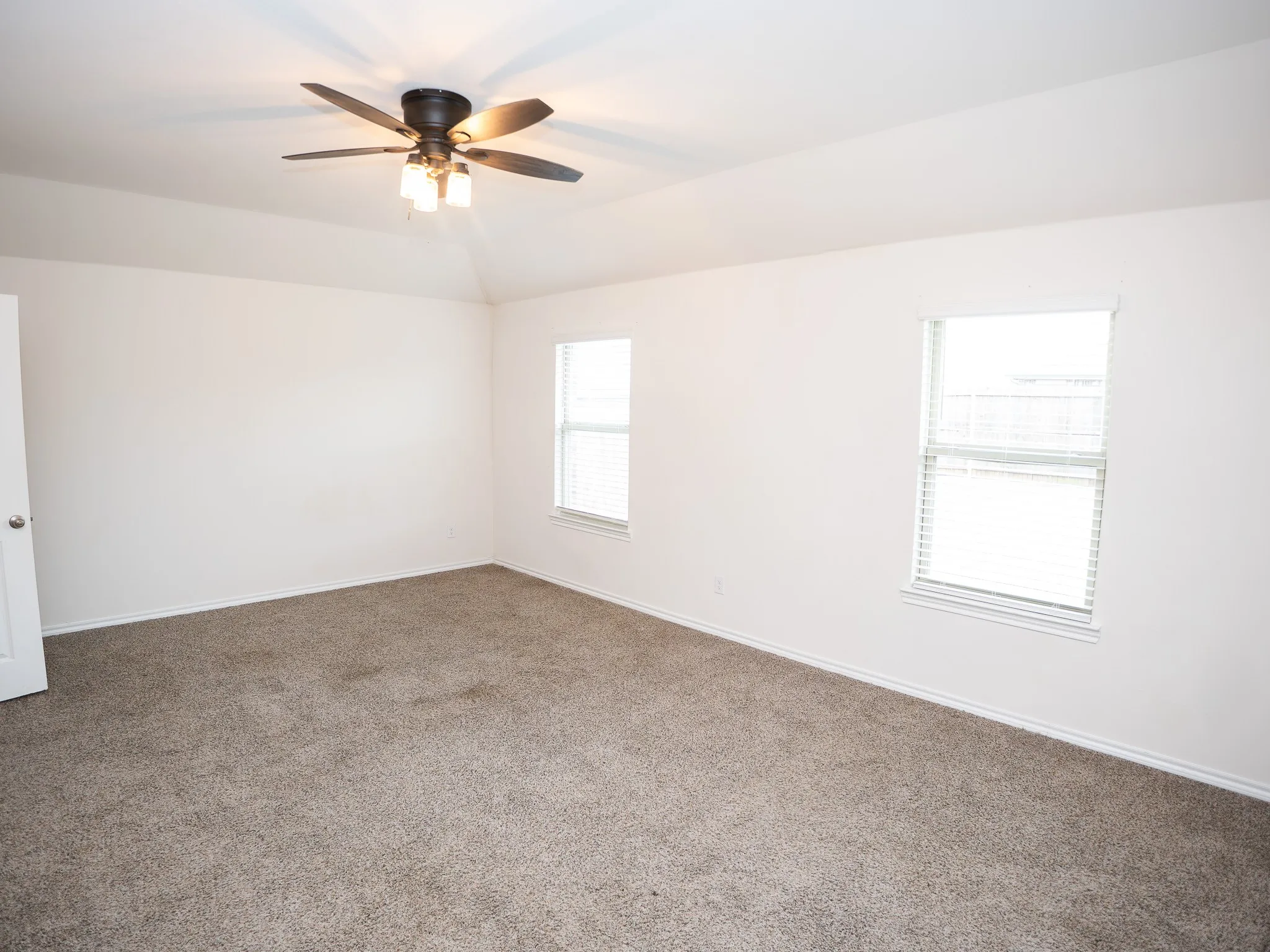 Spacious Master room featuring vaulted ceilings, light neutral walls, and plush carpeting