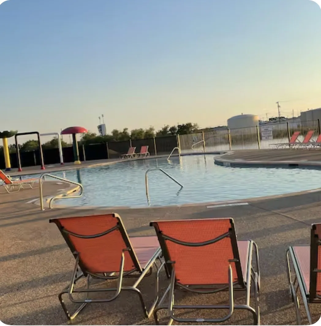 Resort-style swimming pool featuring a curved design, integrated handrails, and a surrounding concrete deck