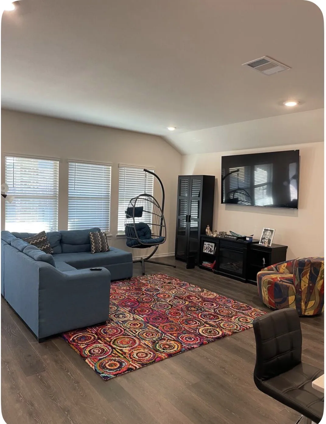 Vaulted ceiling living area featuring multiple windows with blinds, recessed lighting, wood-finish flooring, and a built-in electric fireplace unit