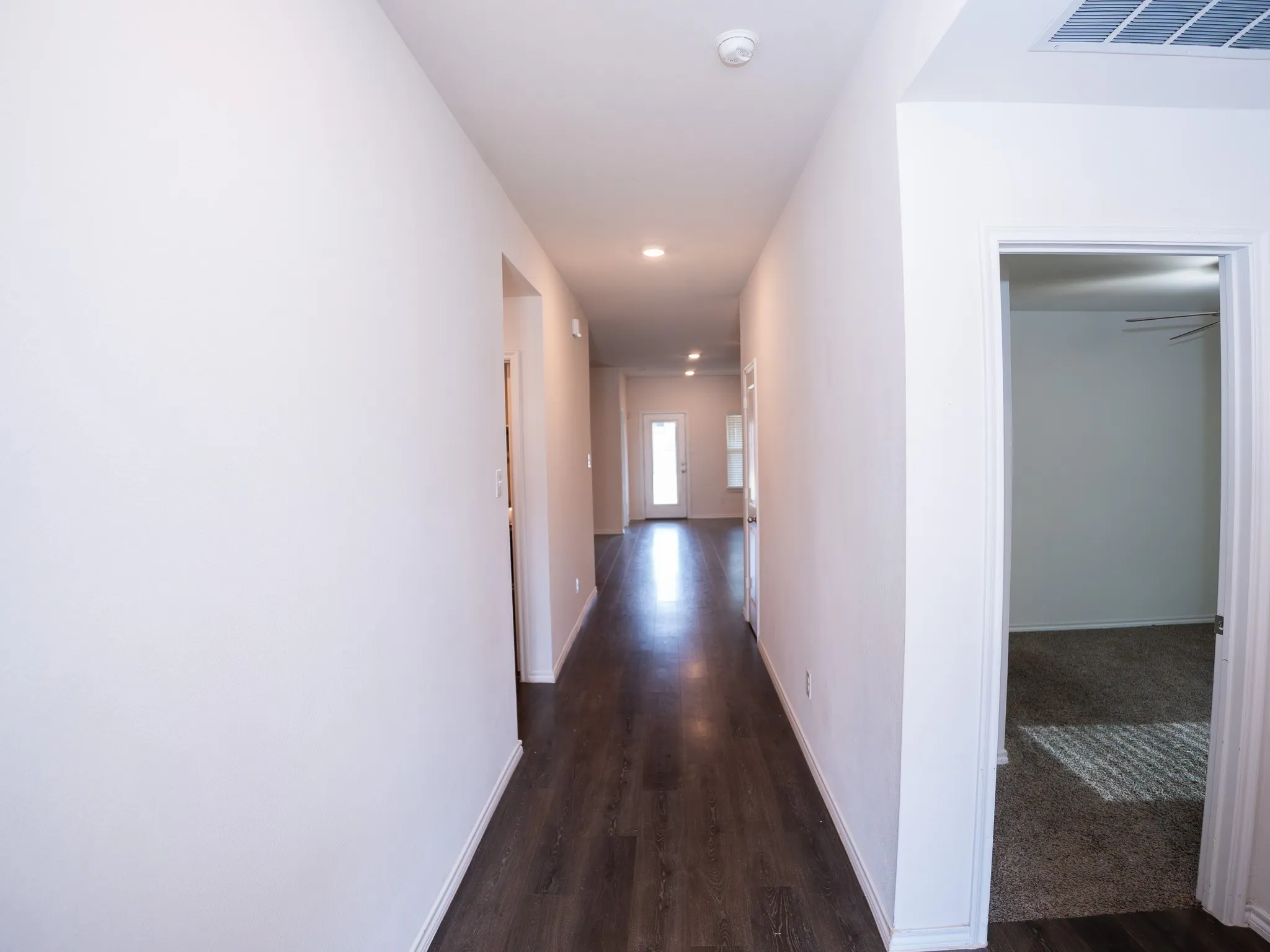 Long hallway featuring wood-finish flooring and recessed lighting