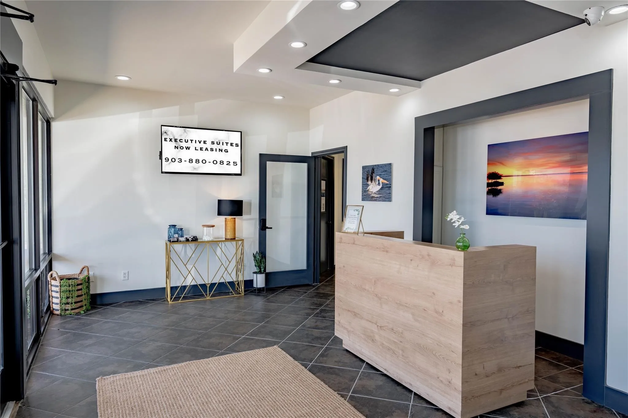 Reception area featuring a wood-finish reception desk, dark tile flooring, and recessed ceiling lighting