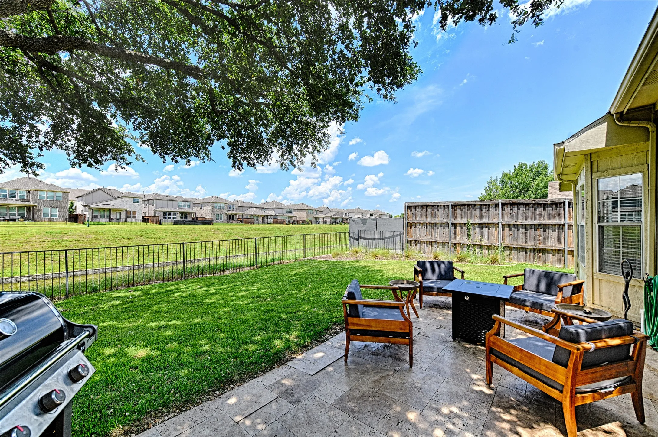 Expansive backyard featuring a stone paver patio, a perimeter black metal fence, and a wooden privacy fence. Backyard faces Canal.