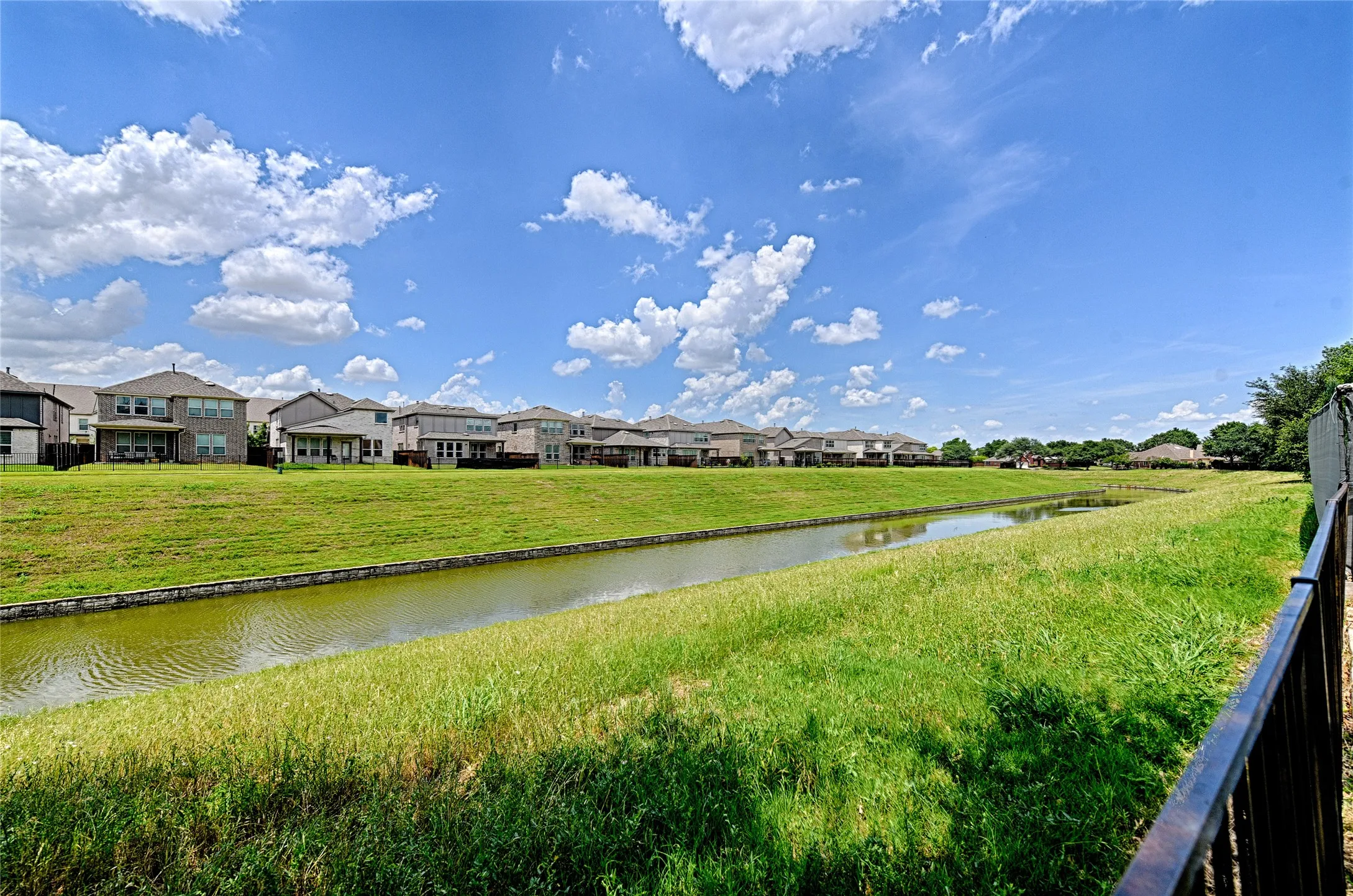 Expansive green space featuring a water channel with stone retaining walls, surrounded by manicured grassy embankments