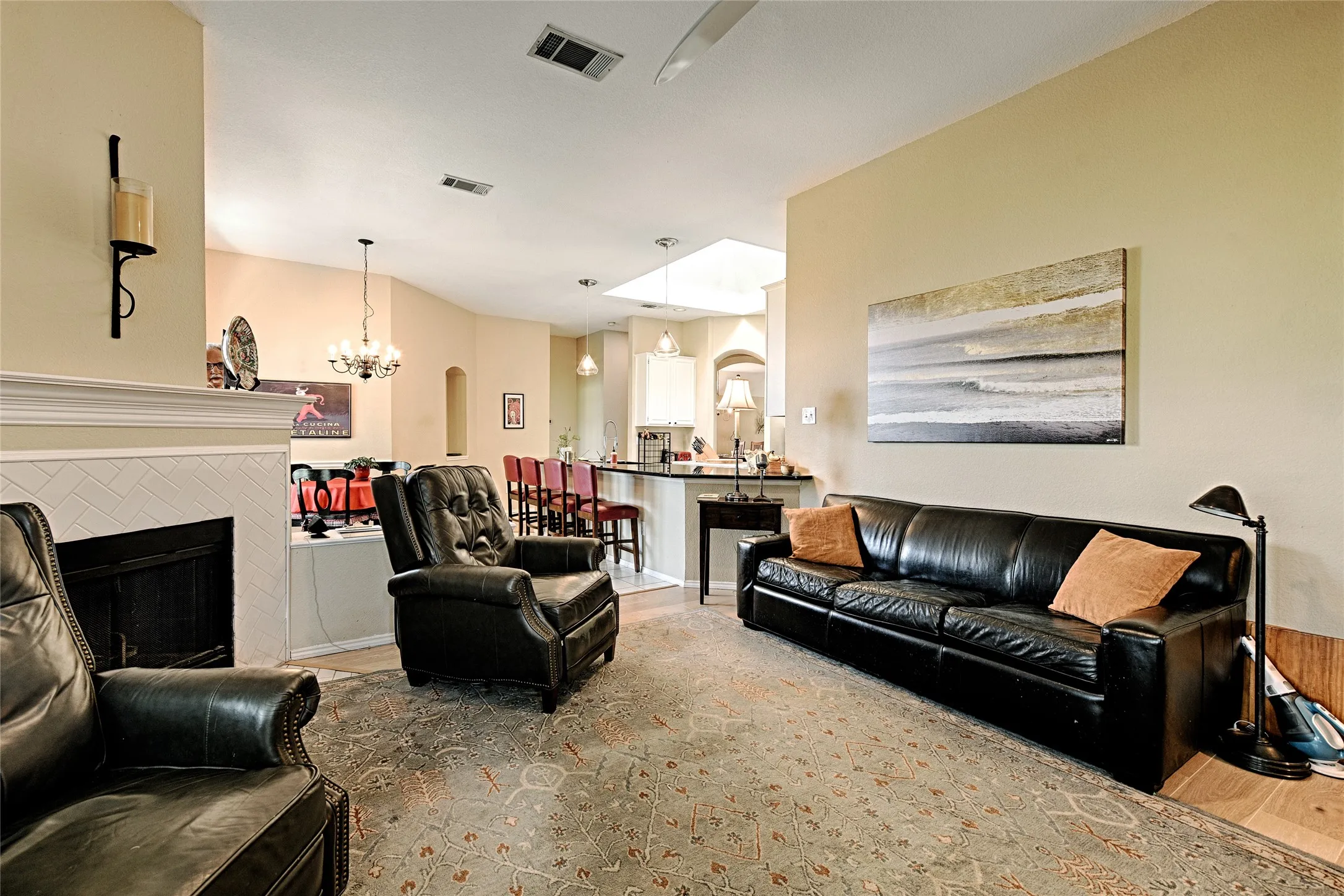 Living space featuring a tiled fireplace with mantel, vaulted ceilings, and a skylight