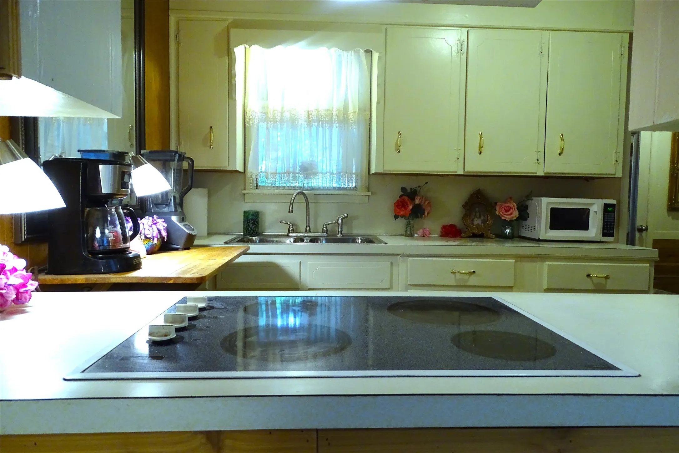 Built-in electric cooktop set into a light-toned countertop, complemented by white cabinetry with gold-tone hardware