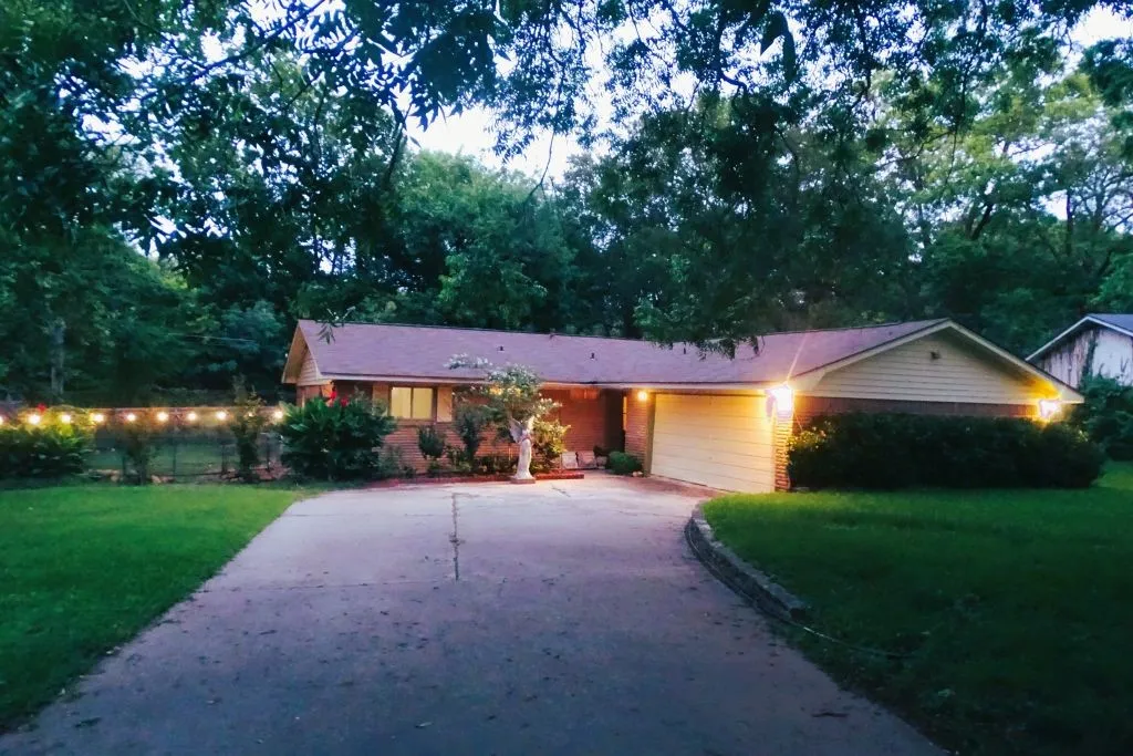 Single-story residence featuring a brick and siding exterior, an attached garage, a paved driveway, and mature landscaping
