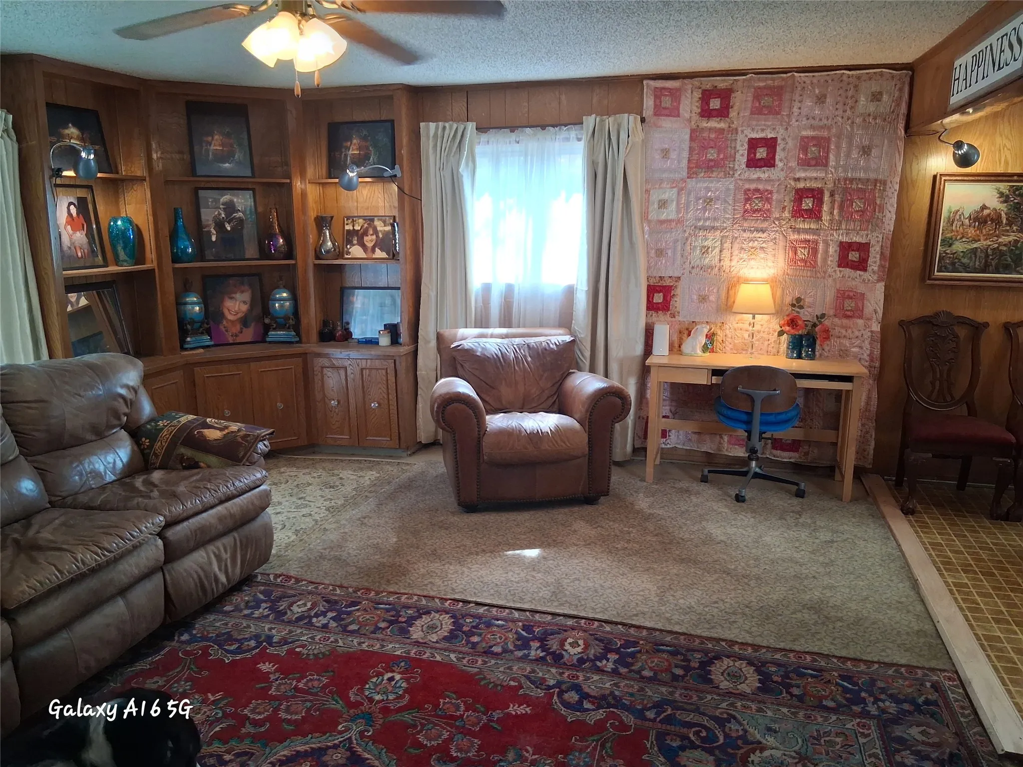 Carpeted living area featuring wood-paneled walls and a built-in corner shelving unit