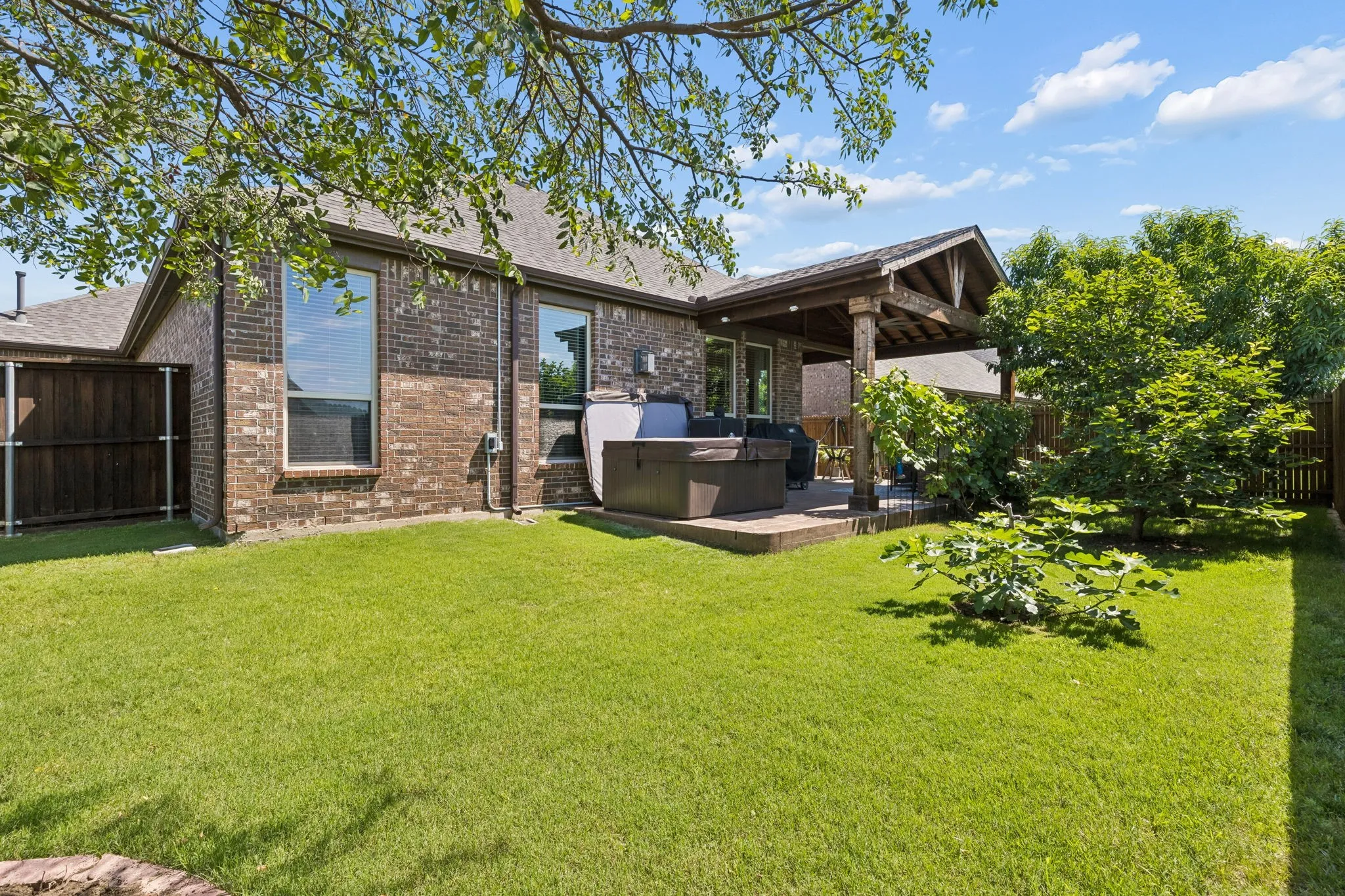 A great view of the yard and relaxing Hot Tub that conveys with the property along with attached Natural Gas Grill