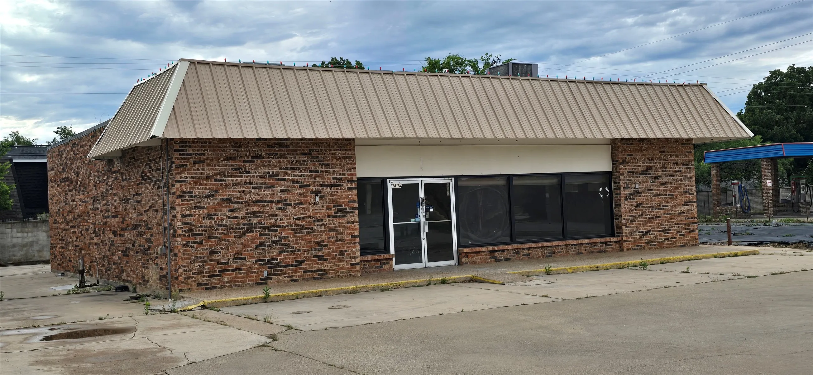 Brick exterior building featuring a metal roof and prominent storefront windows