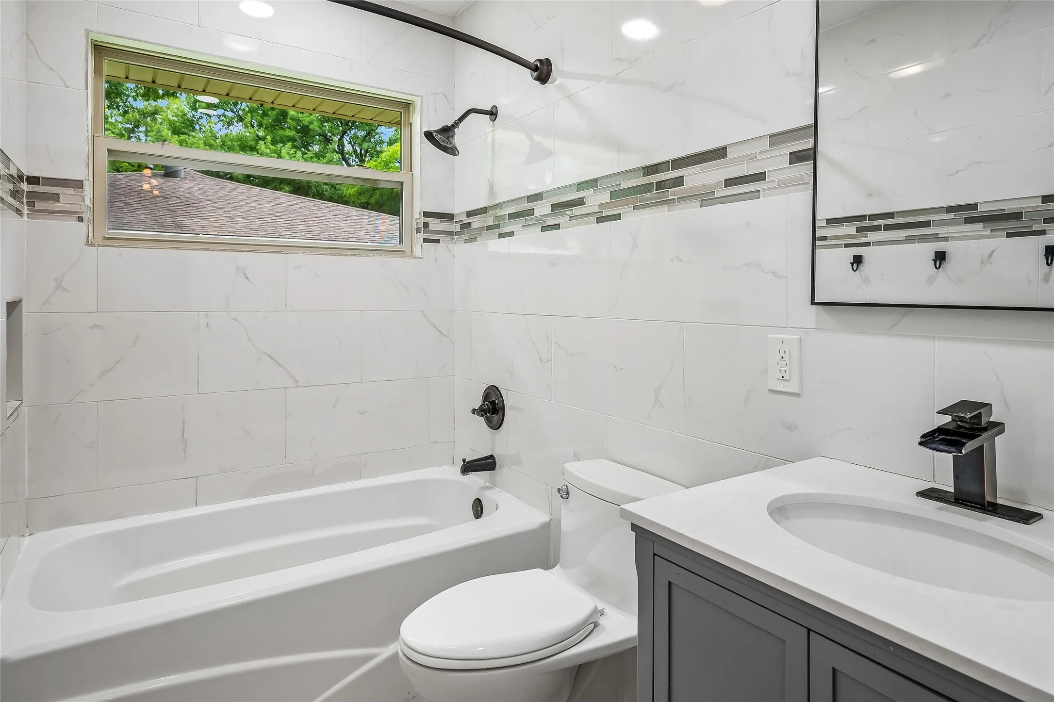 Modern bathroom featuring white tile walls with a decorative mosaic accent band