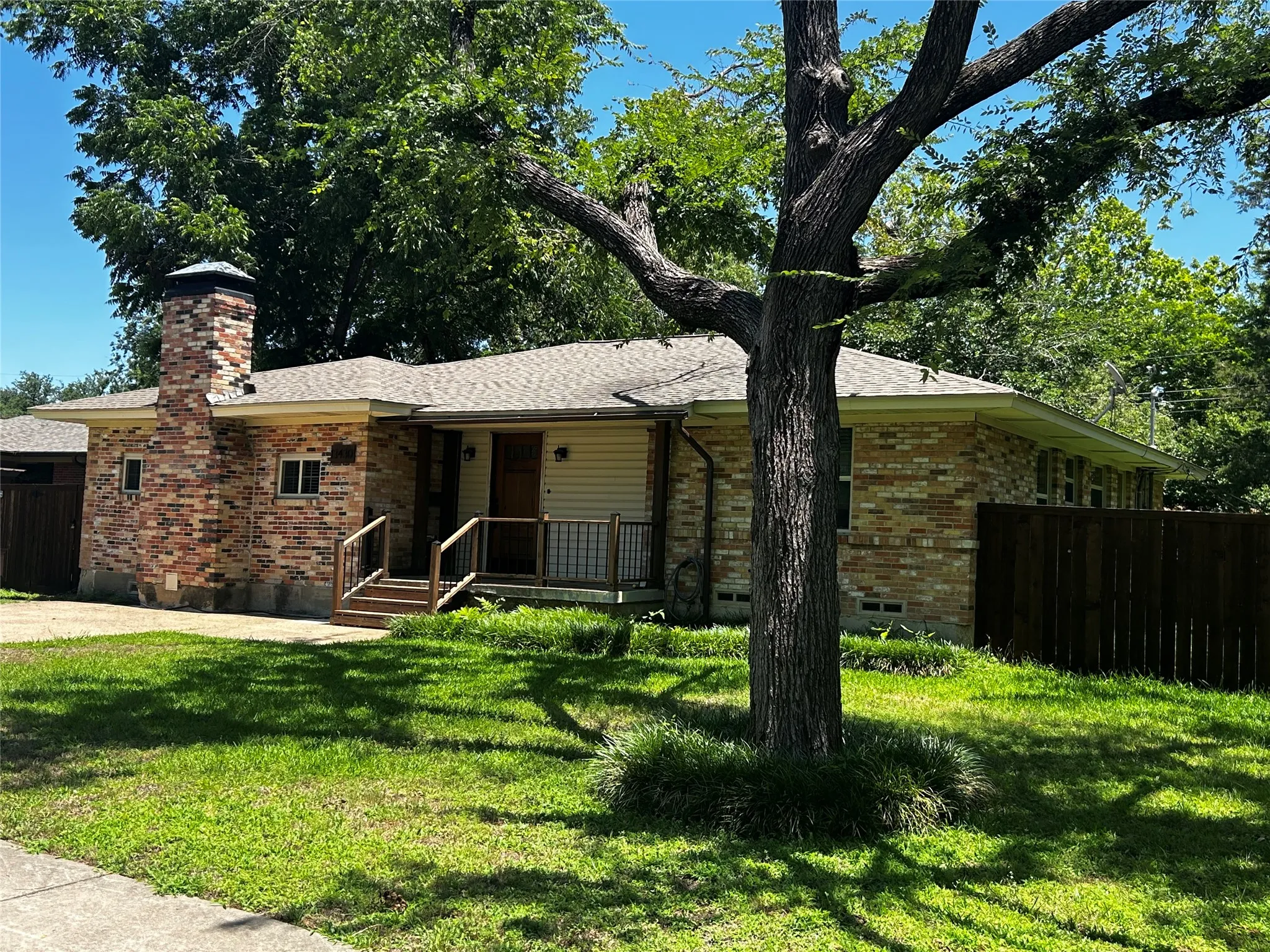 Single-story residence featuring a brick and siding exterior, a prominent brick chimney, and a front porch with wood steps and railings