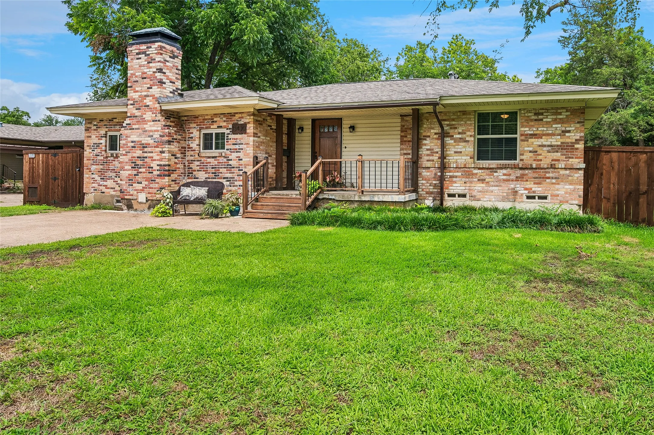 Brick-clad exterior with a prominent chimney, inviting front porch, and a well-kept lawn