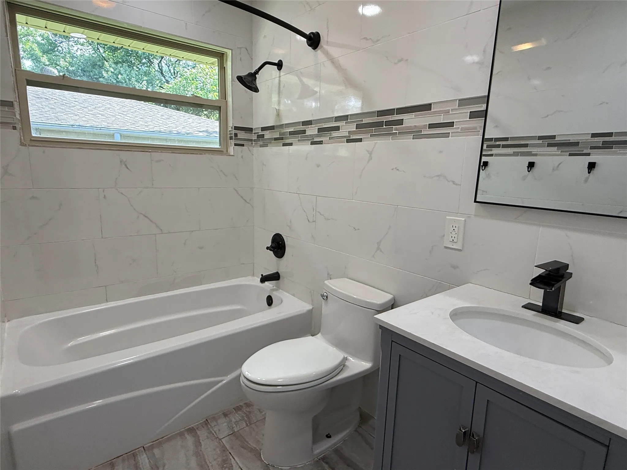 Bathroom featuring a white bathtub, toilet, and a vanity with a white countertop and gray cabinetry