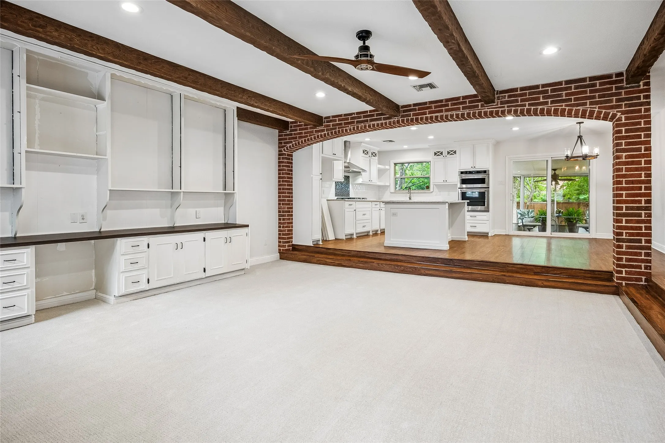 Spacious room featuring exposed wood beams and recessed lighting